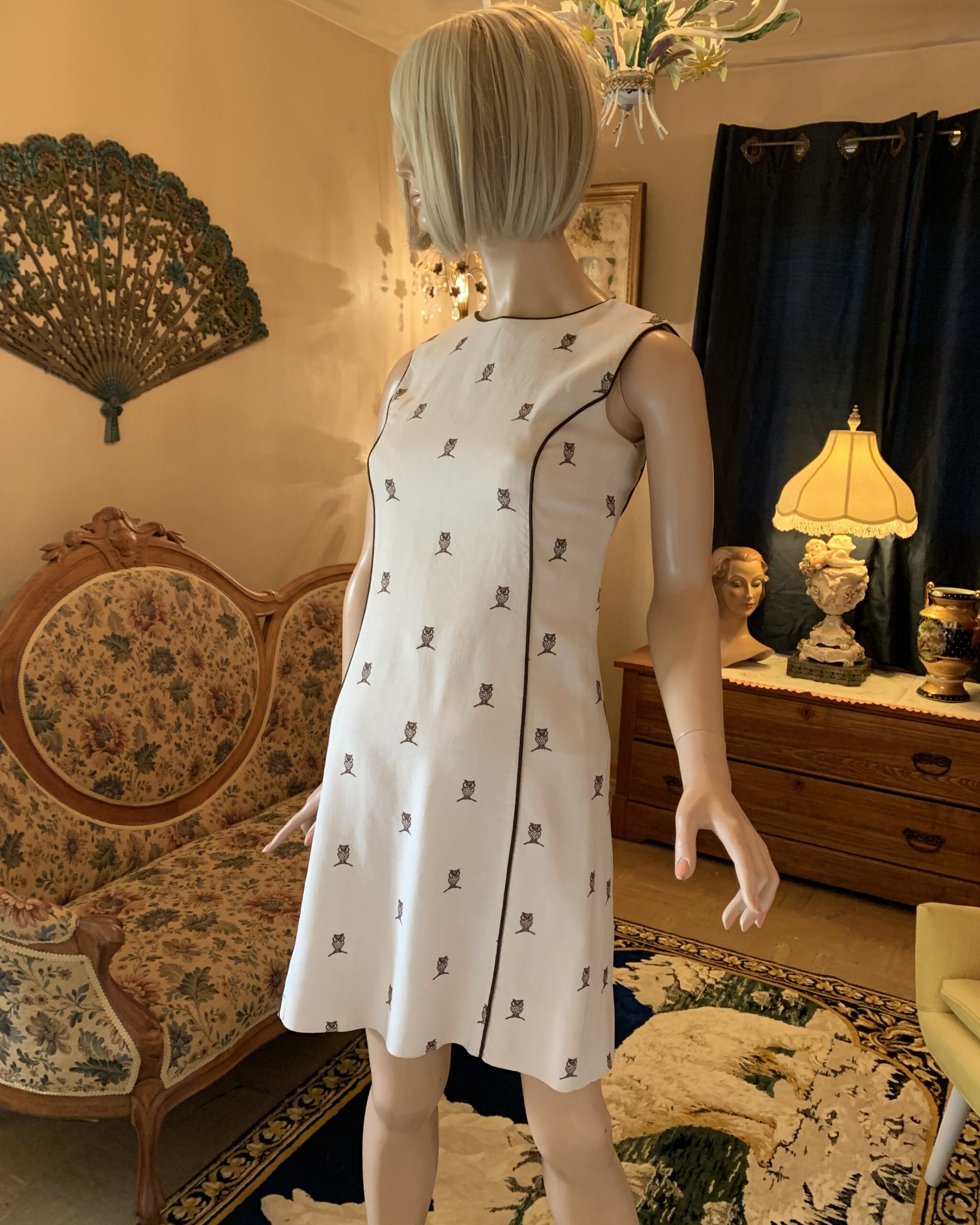 Vintage 1960s House of Lords novelty owl print shift dress with sleeveless silhouette, cream textured fabric, and brown piping trim.