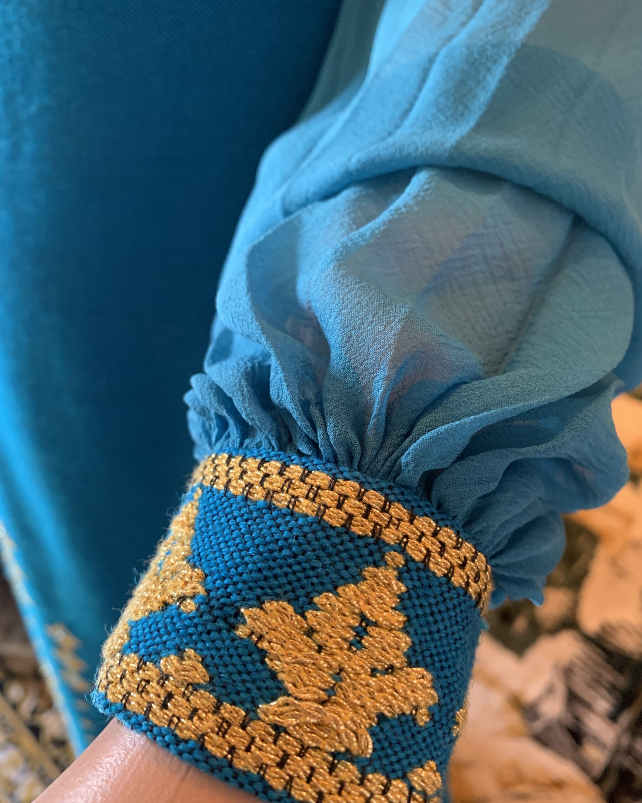 Detail of sheer pleated chiffon sleeve gathered into woven gold embroidered cuff with narrow wrist closure on 1970s Greek gown.