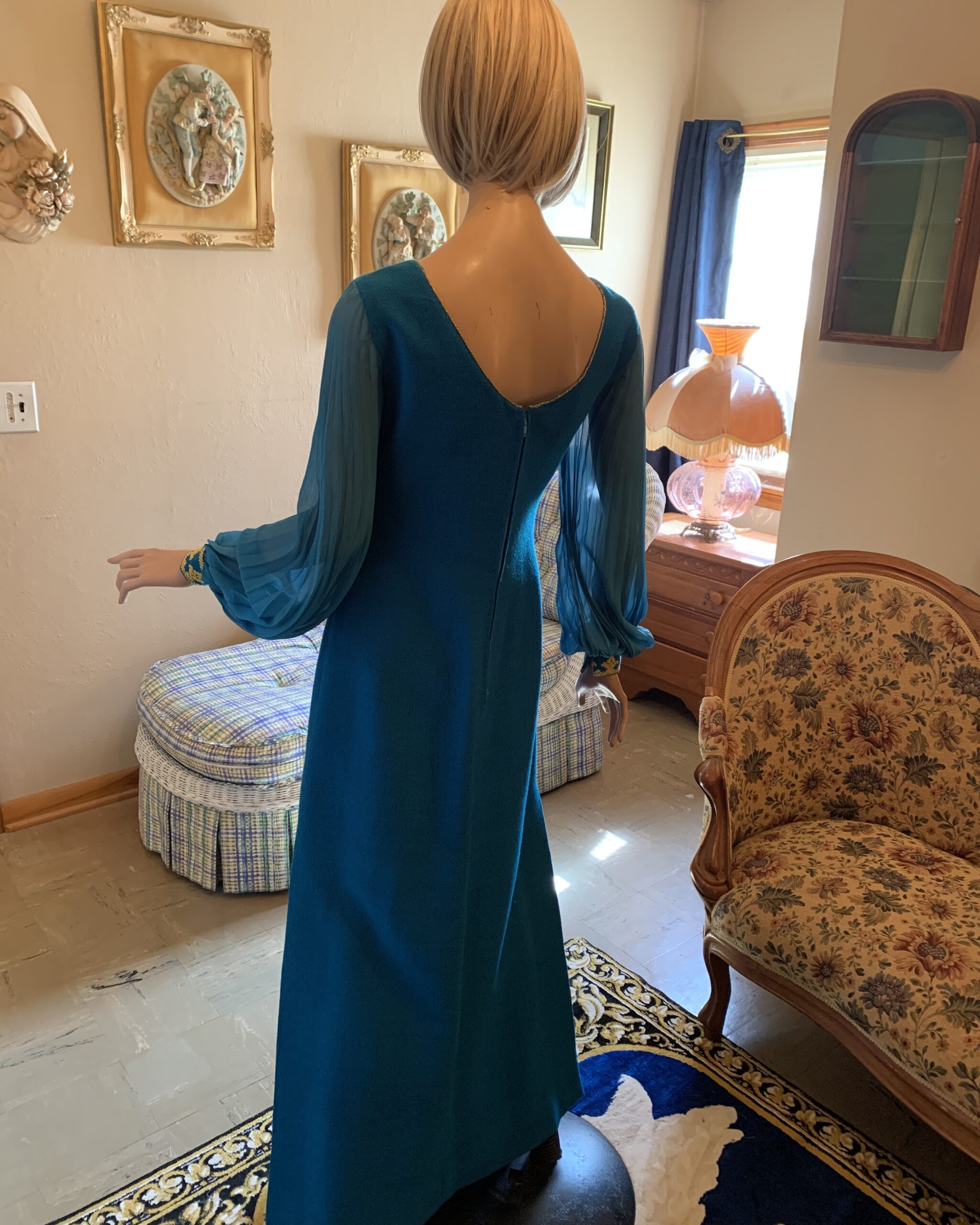 Back view of 1970s Nikos and Takis Greek evening gown featuring deep scoop back, sheer pleated sleeves, and flowing full-length silhouette.