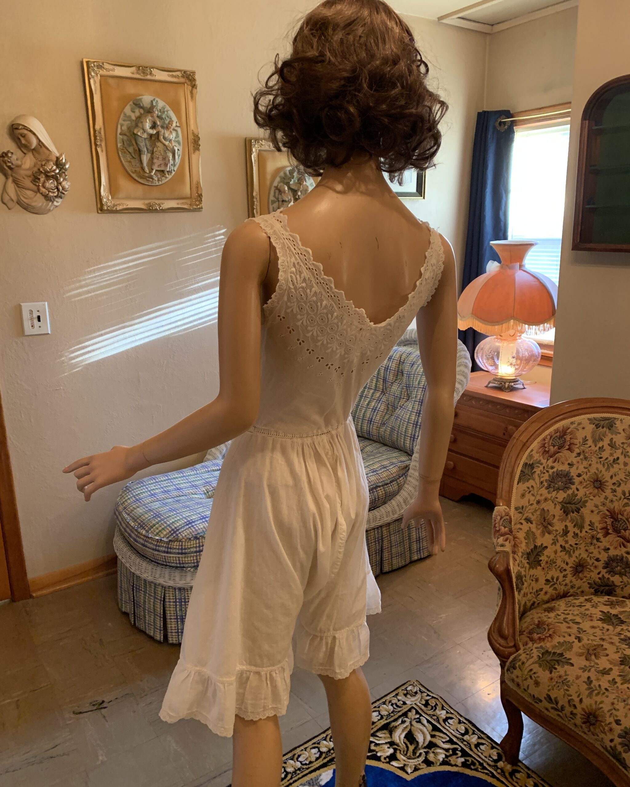 Back view of antique Edwardian white cotton combination step-in with embroidered straps, gathered waist, and ruffled leg openings.