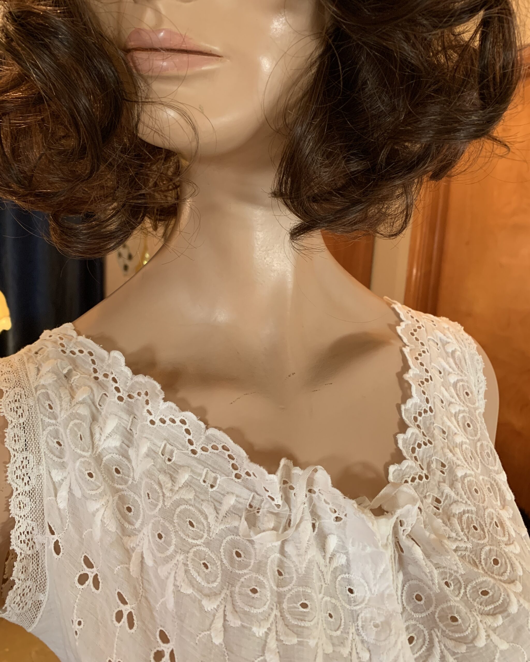 Close-up of antique Edwardian cotton step-in showing embroidered eyelet work and satin tie detail at the neckline.