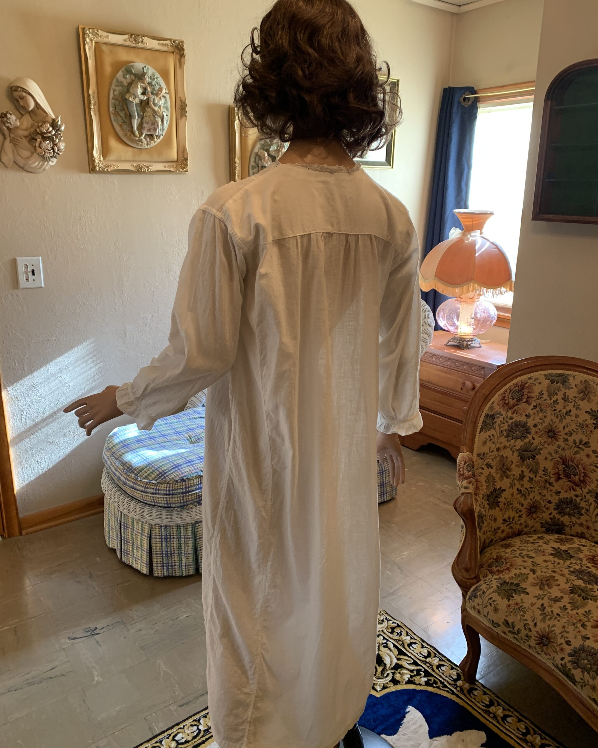 Back view of early 20th-century white cotton nightgown with gathered yoke construction and long sleeves.