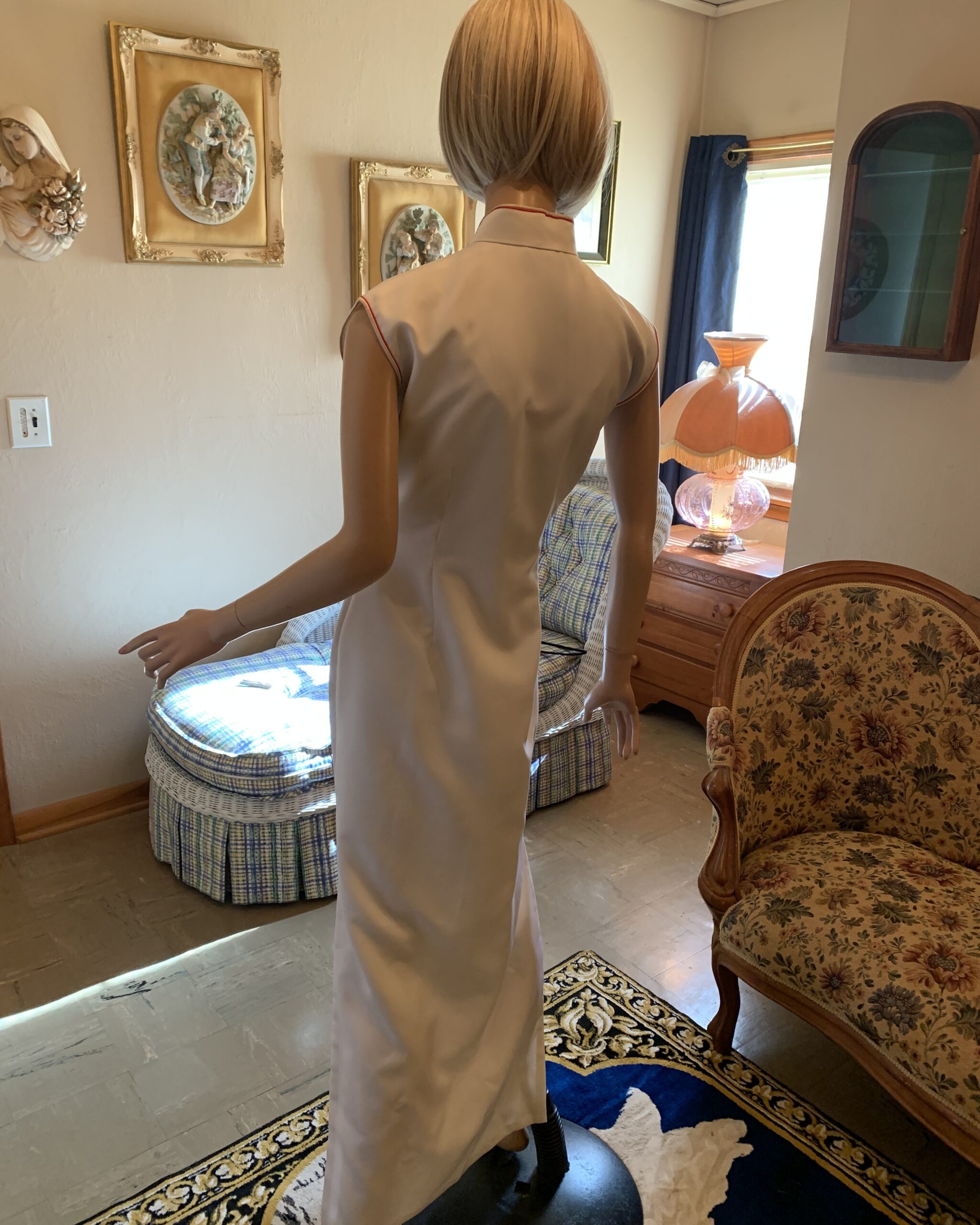Back view of vintage ivory cheongsam dress with fitted silhouette, sleeveless design, and floor-length skirt.