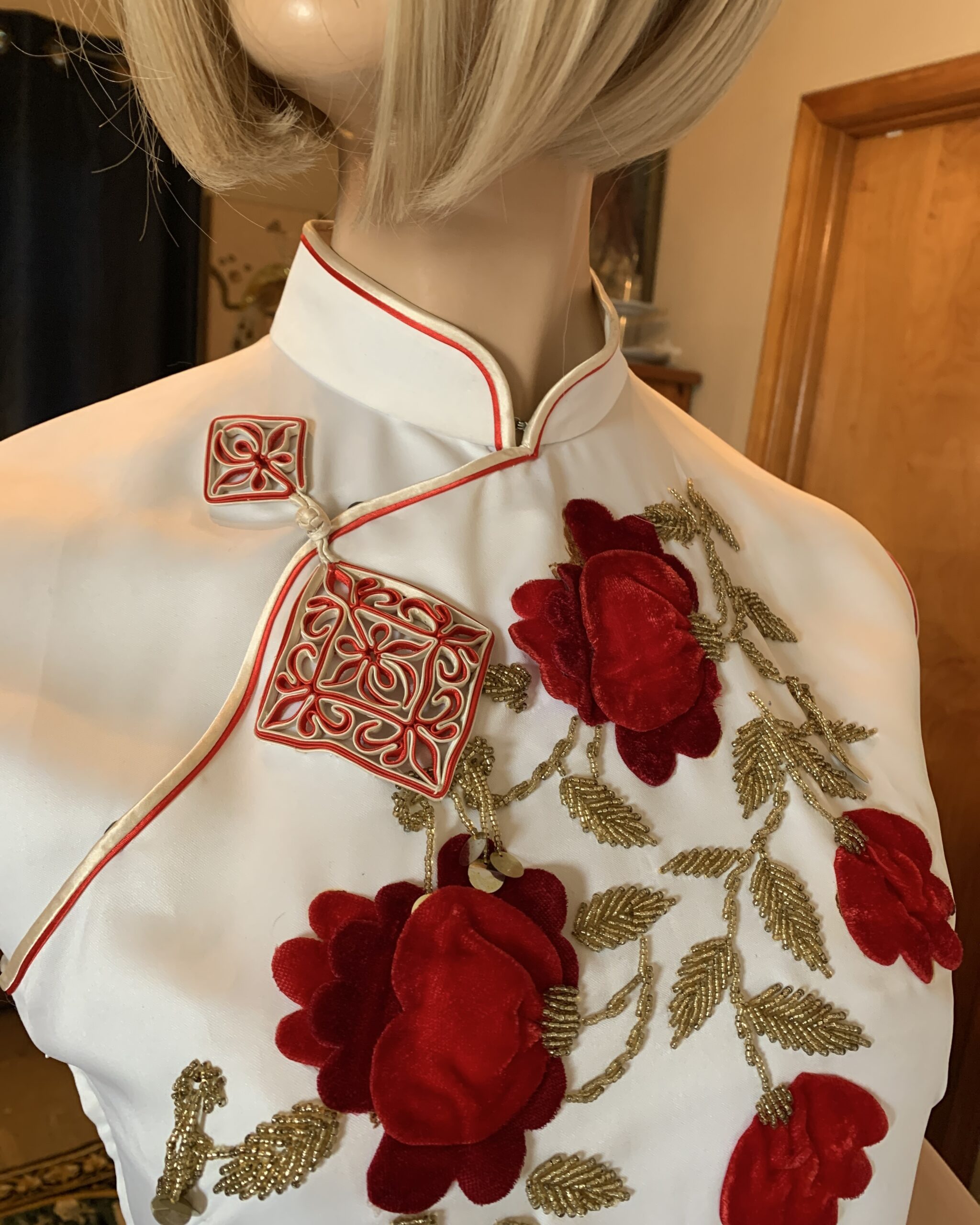 Detail of Mandarin collar and decorative frog closure with red piping, velvet floral appliqué, and gold beaded embroidery.