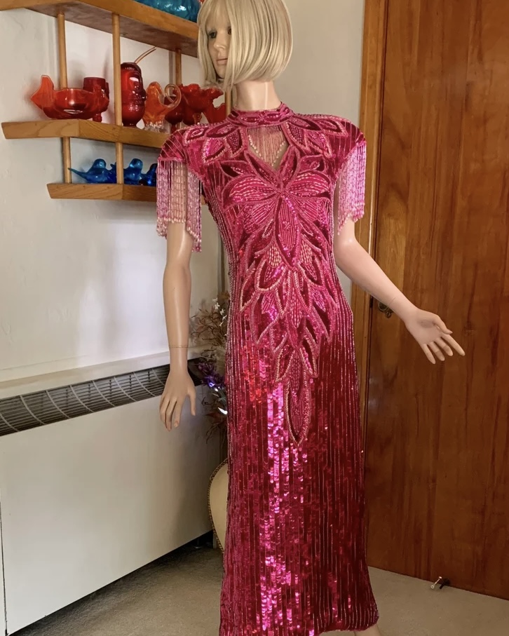 Vintage hot pink beaded sequin evening gown by Sequins Originals displayed on mannequin with fringe sleeves and fitted column silhouette.