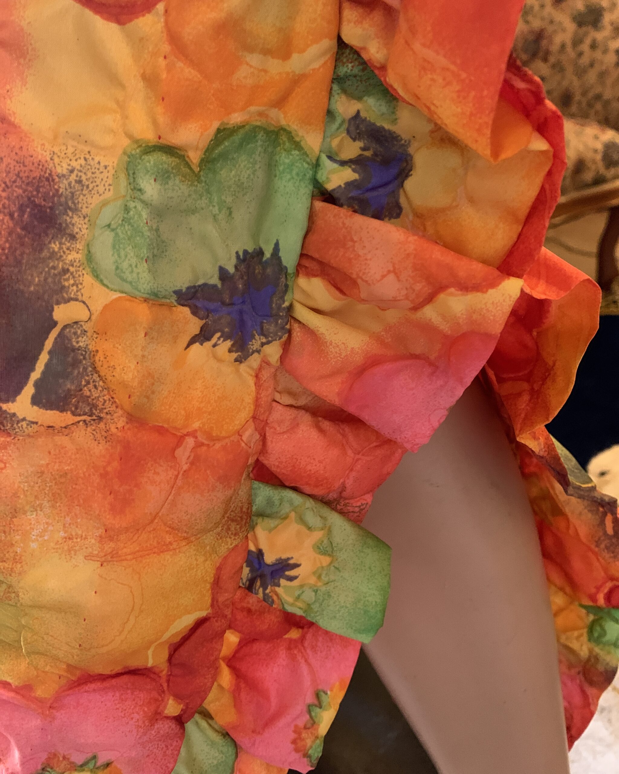 Close-up of the ruffled hem on a colorful psychedelic floral resort dress.