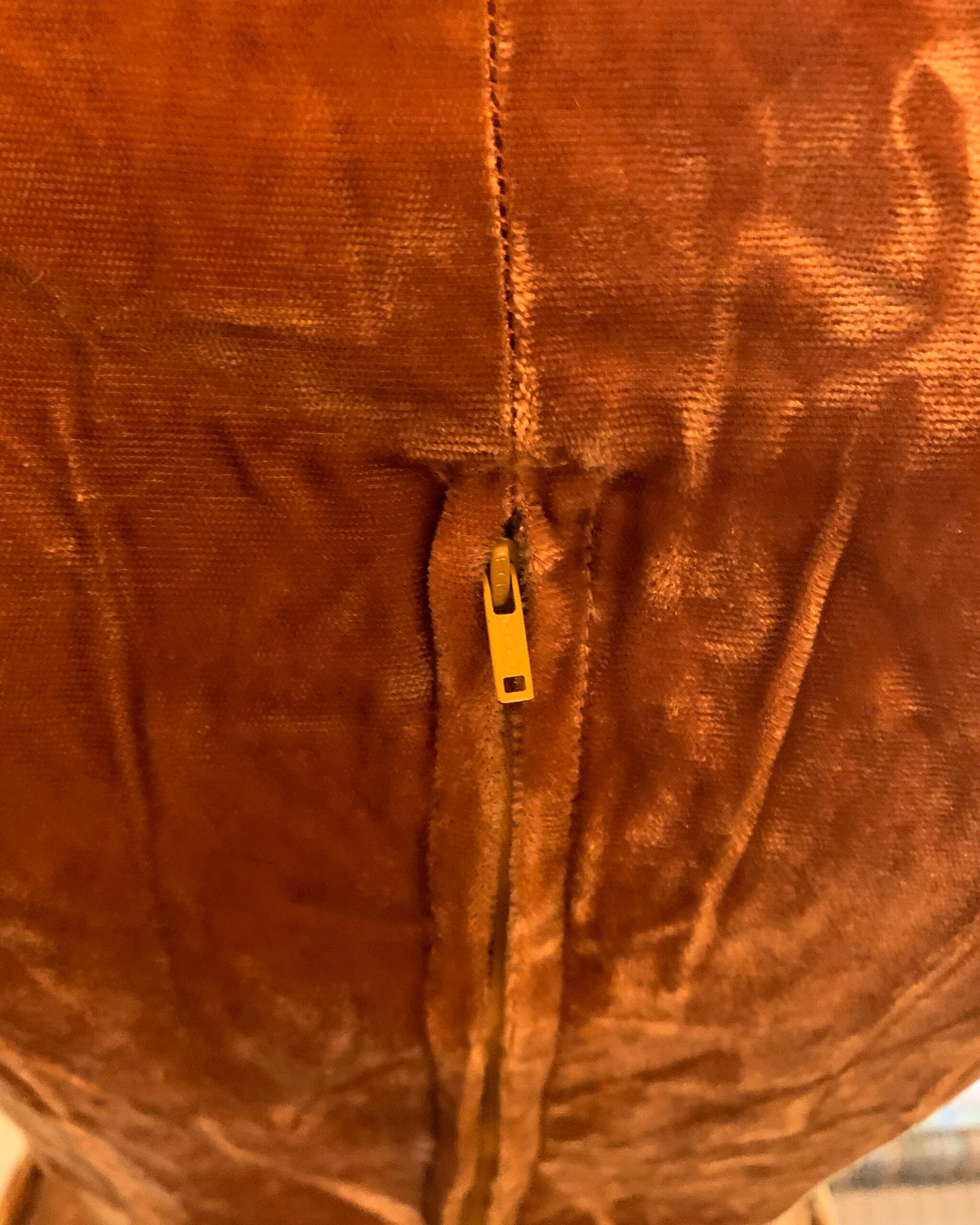 Close-up of the metal side zipper closure on a vintage golden velvet dress, highlighting original mid-century construction.