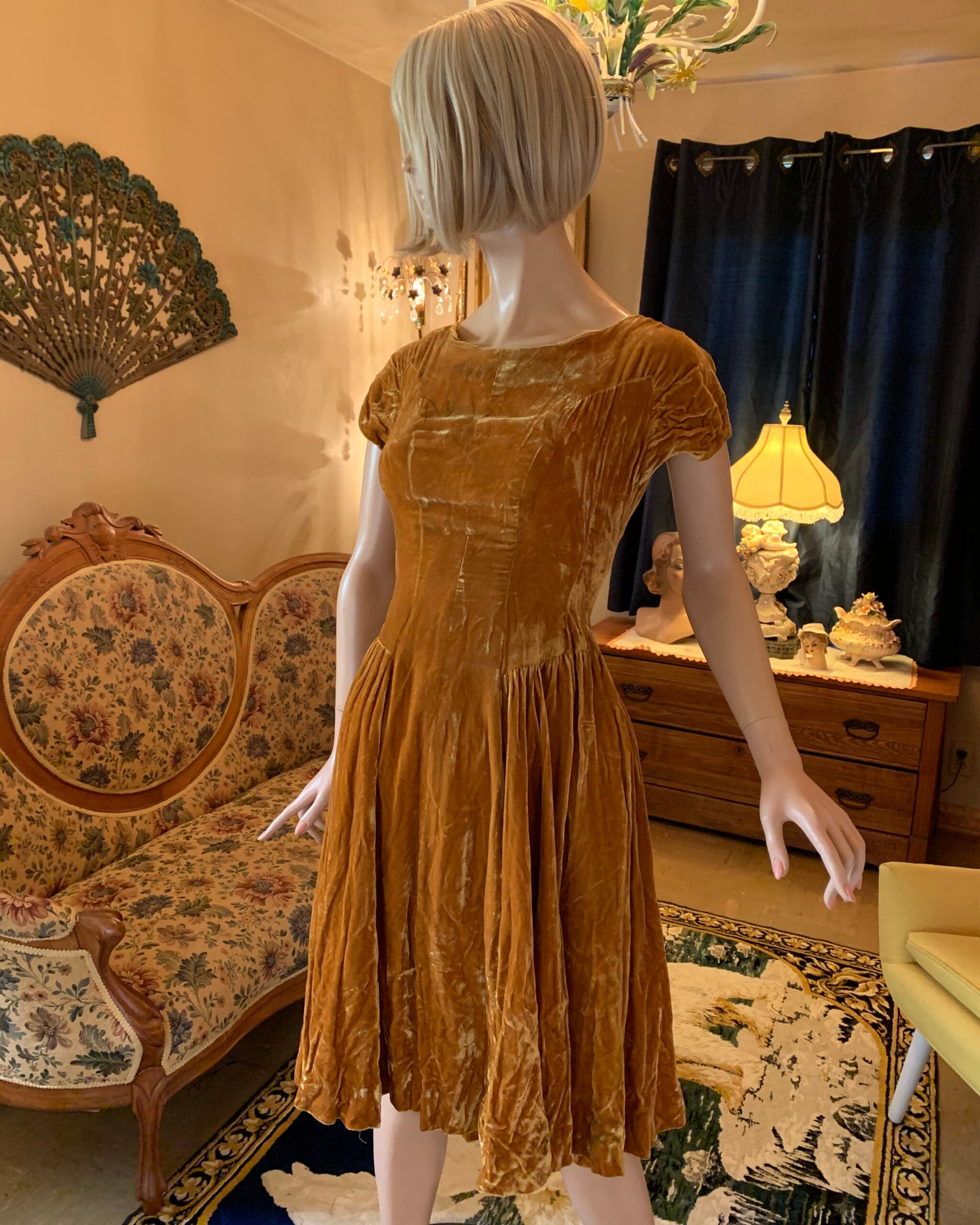 Vintage golden velvet party dress with cap sleeves, fitted bodice, and gathered skirt displayed in the salon.