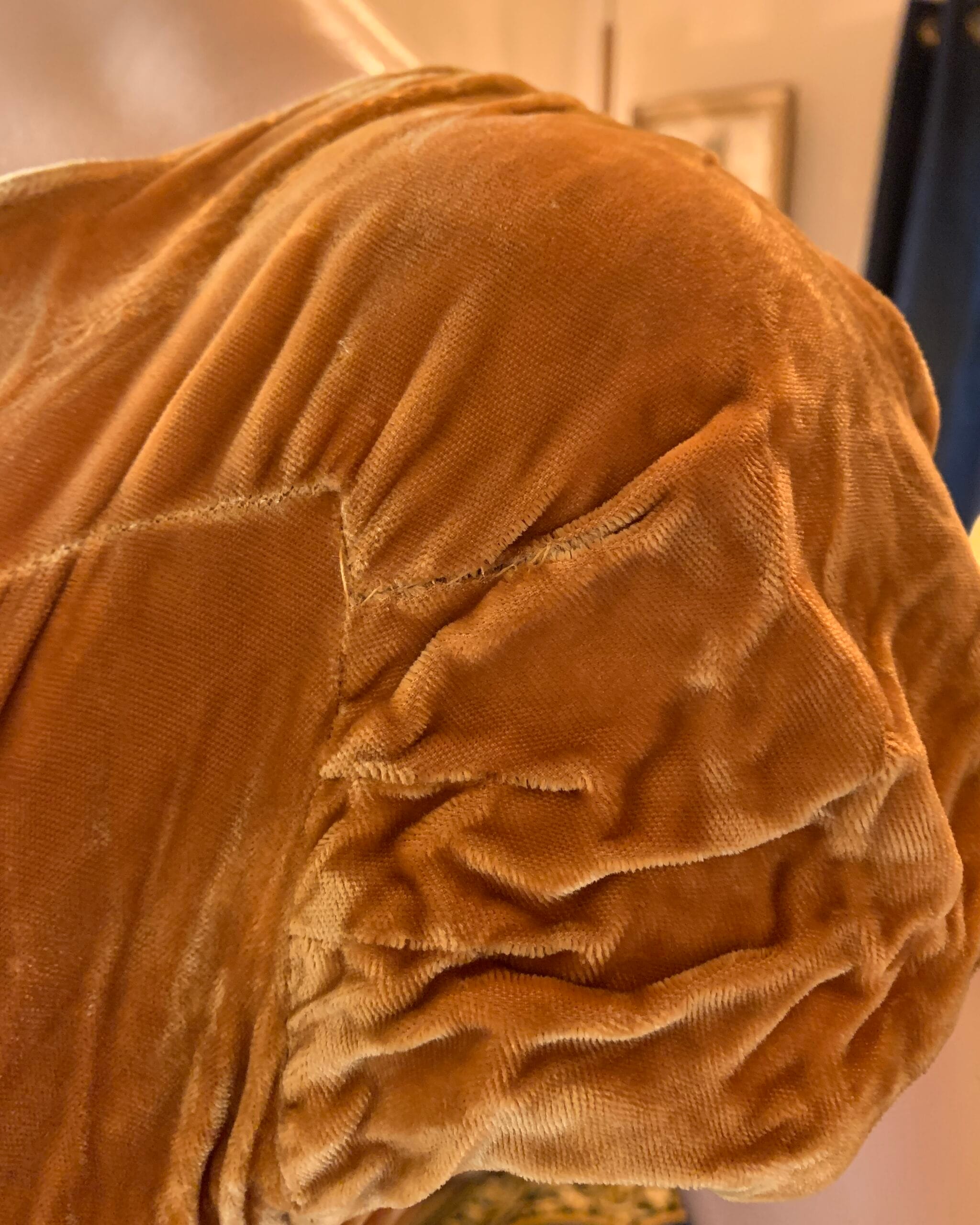Close-up of the gathered cap sleeve detail on a vintage golden velvet dress, showcasing the texture and drape of the velvet fabric.