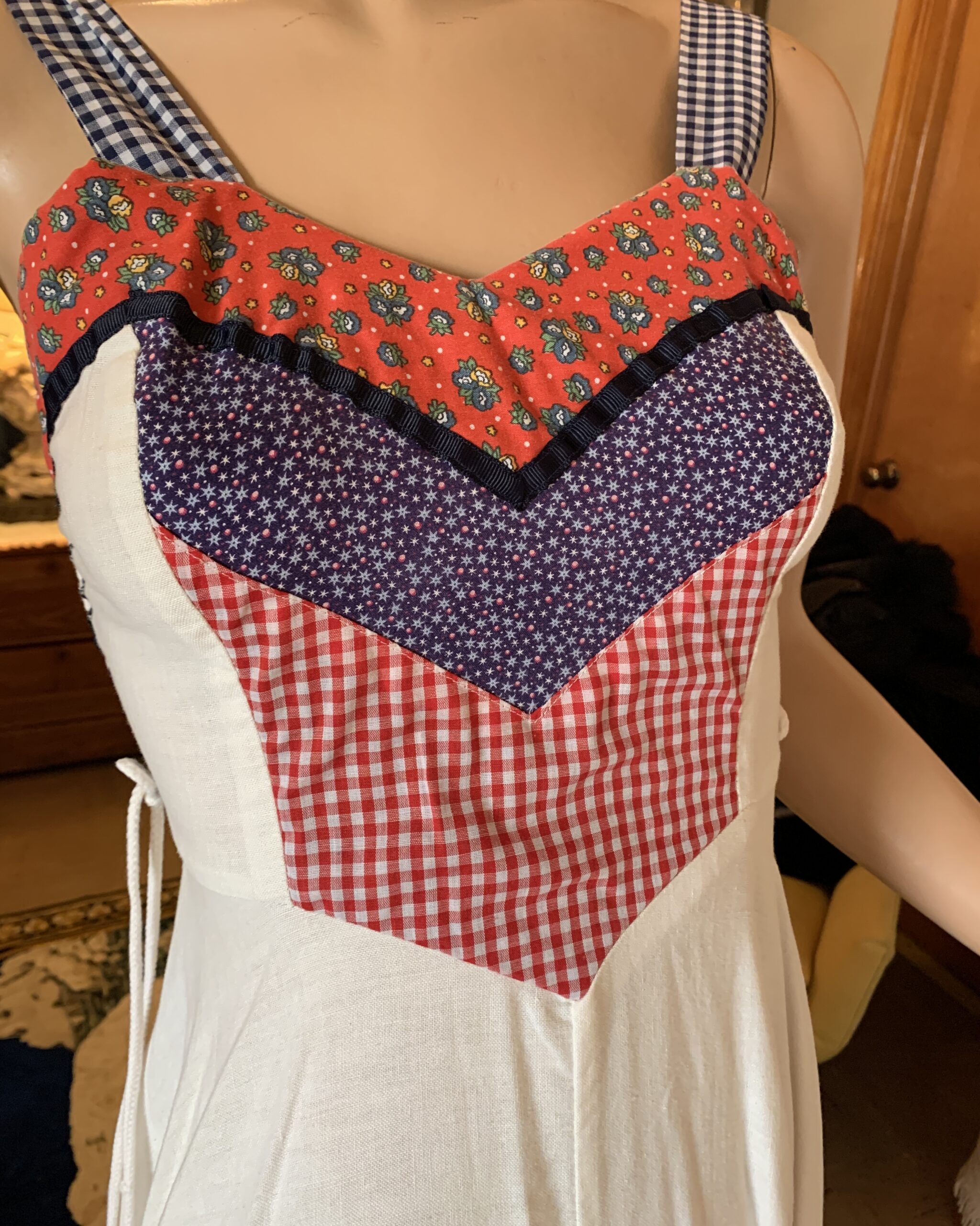 Close-up of Gunne Sax patchwork bodice with red floral calico, blue star print, gingham panels, and navy trim.