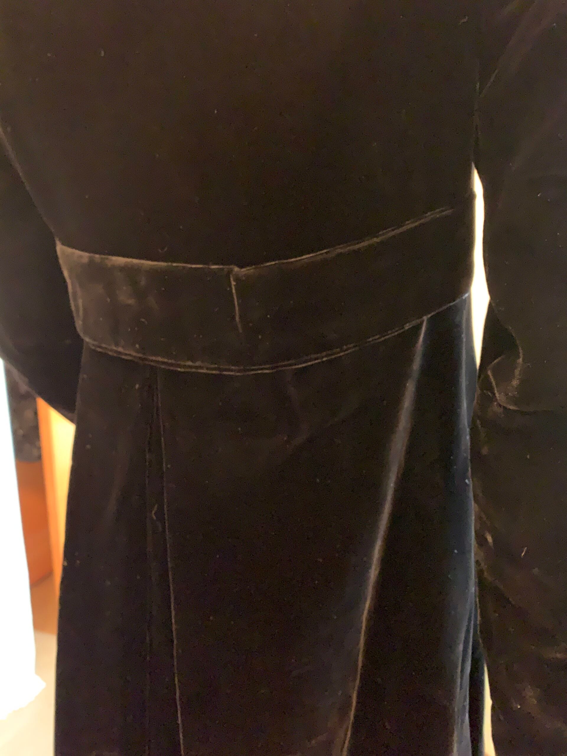 Close-up of black velvet opera coat highlighting the shaped waist and back sash construction.