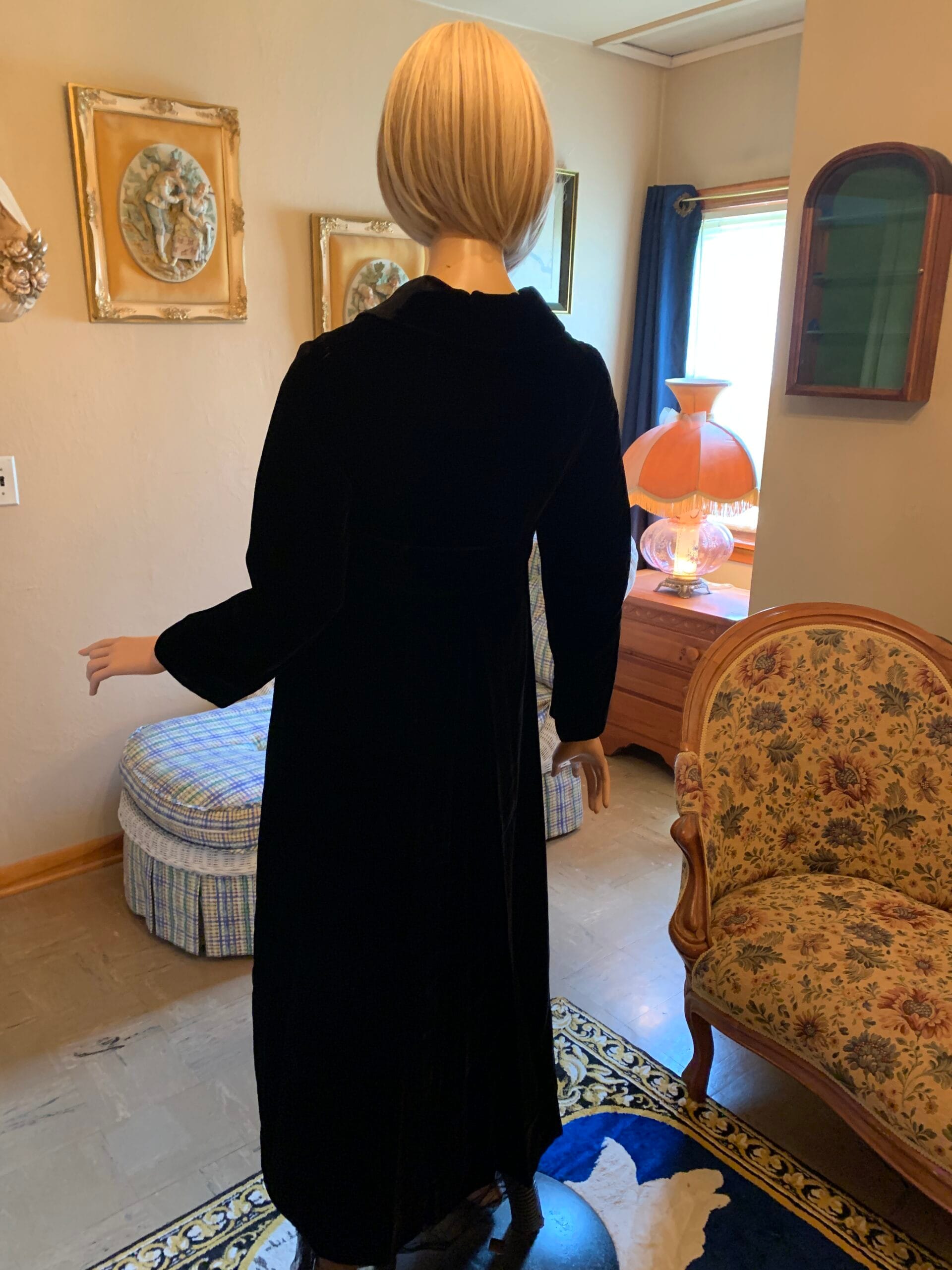 Rear view of black velvet opera coat featuring a tailored silhouette and decorative back sash detail.