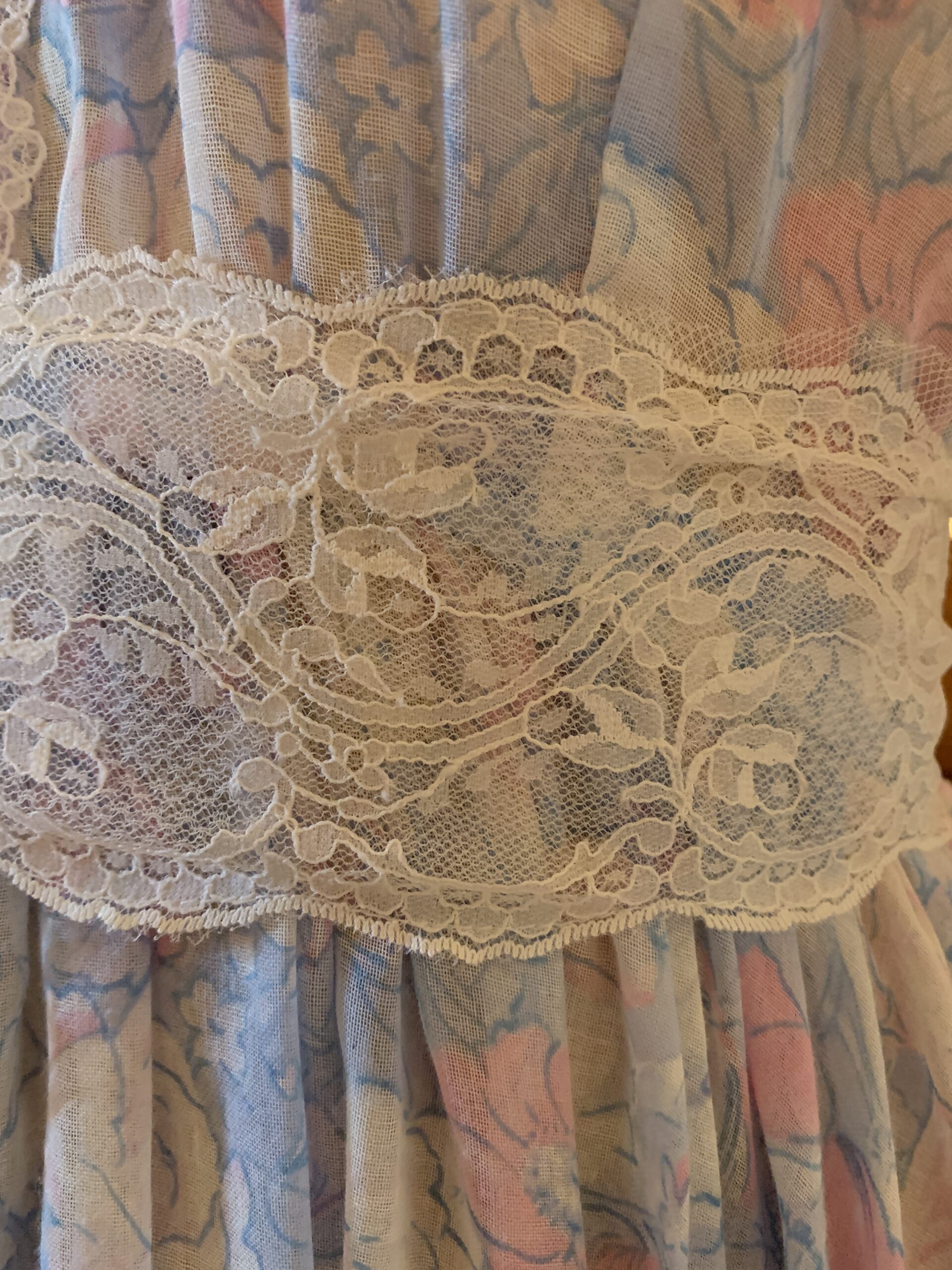 Close-up of lace yoke, floral voile fabric, and front button closure on a handmade vintage prairie dress from The Seamstress Collection.