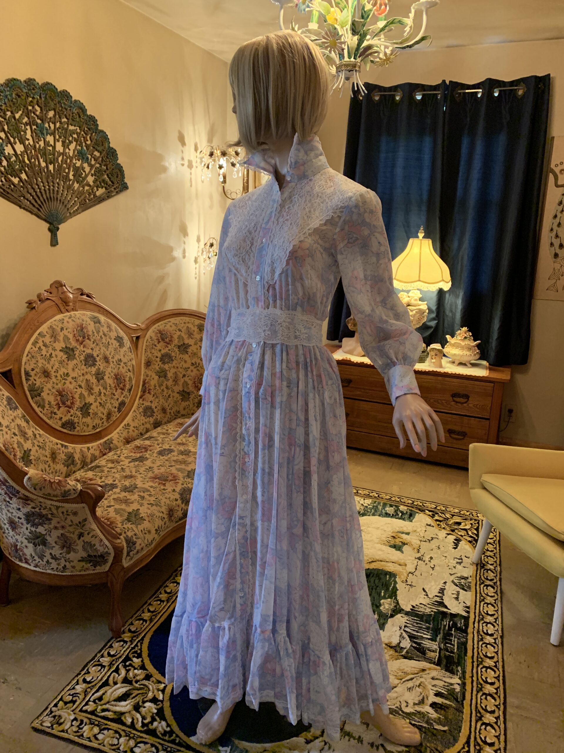 The Seamstress Collection floral voile maxi dress featuring pastel flowers, lace trim, and a full flowing skirt photographed on a mannequin.