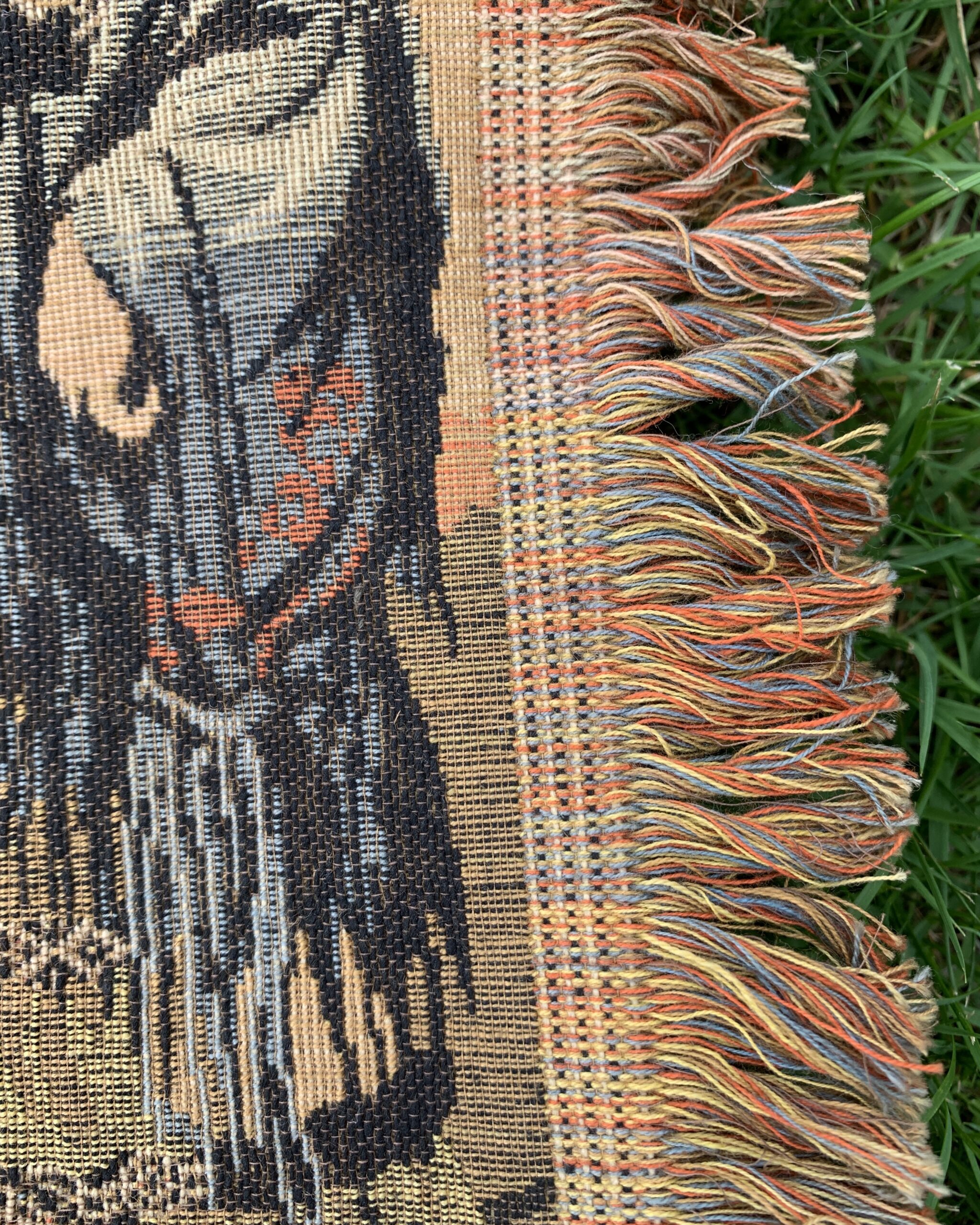 Multicolored woven fringe and textile construction detail from vintage Spanish courtyard tapestry panel.