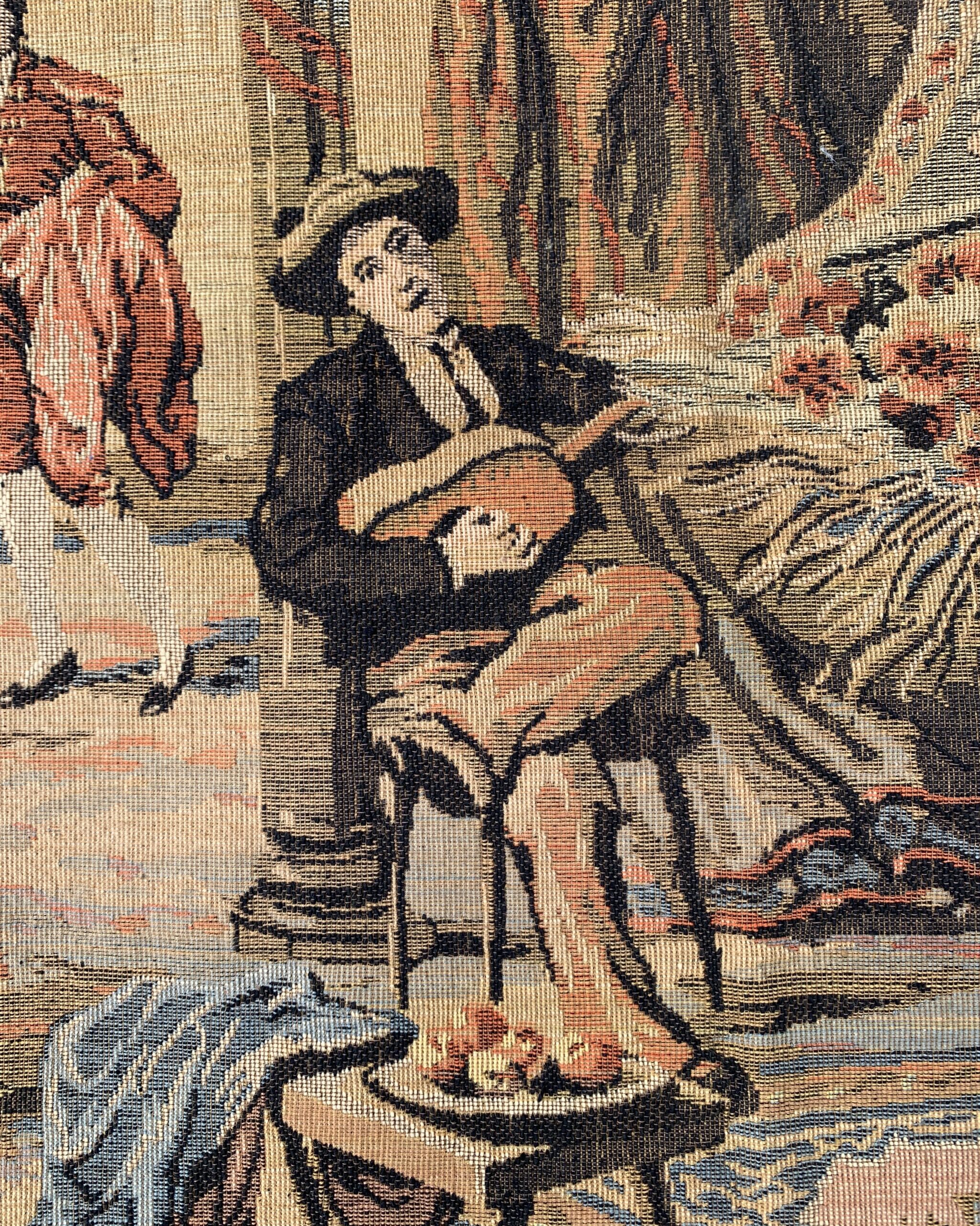 Close-up of seated musician holding a stringed instrument beneath decorative drapery in a woven tapestry scene.