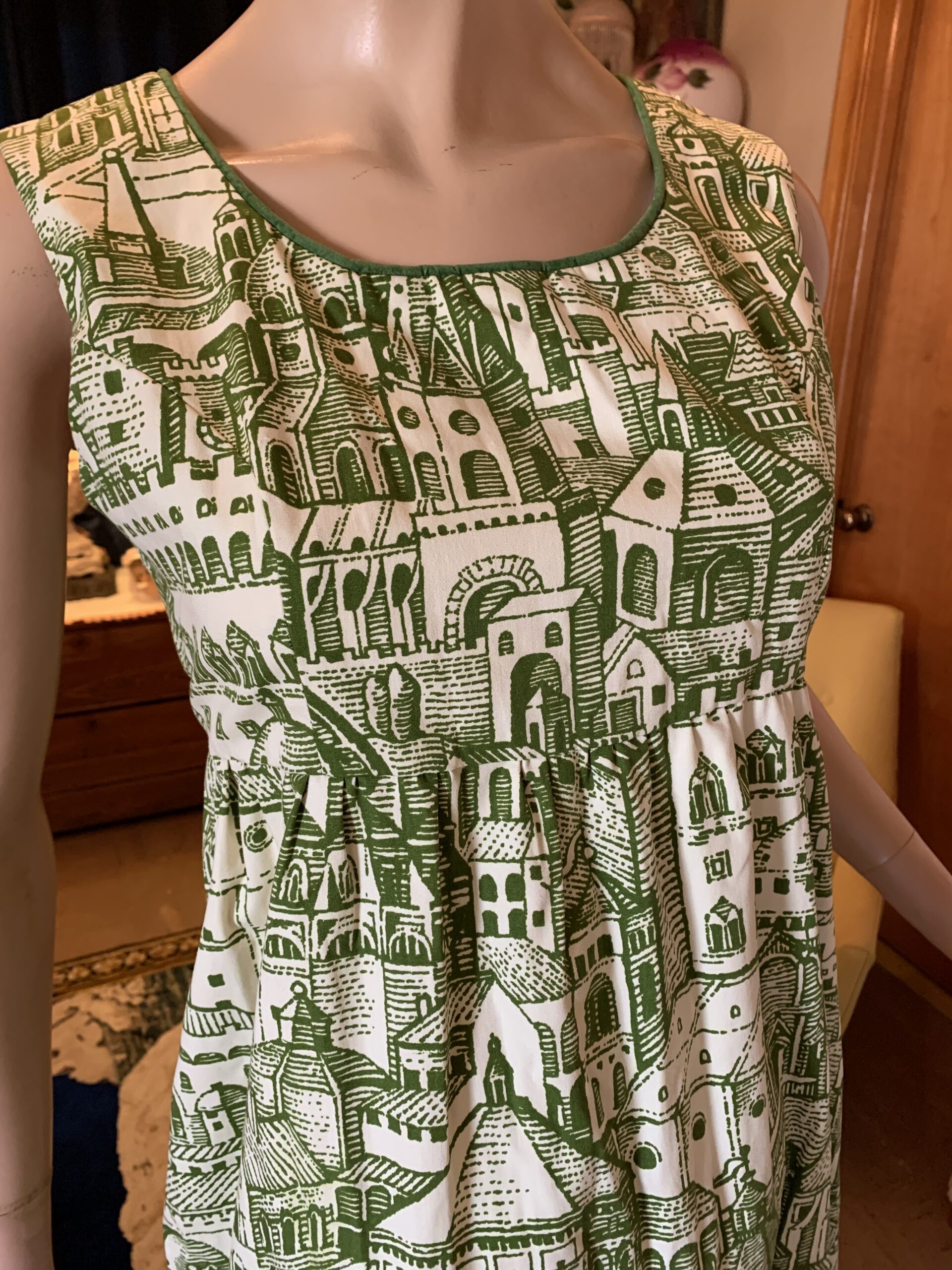 Three-quarter view of handmade Waverly cotton maxi dress with architectural village print, empire waist, and full gathered skirt.