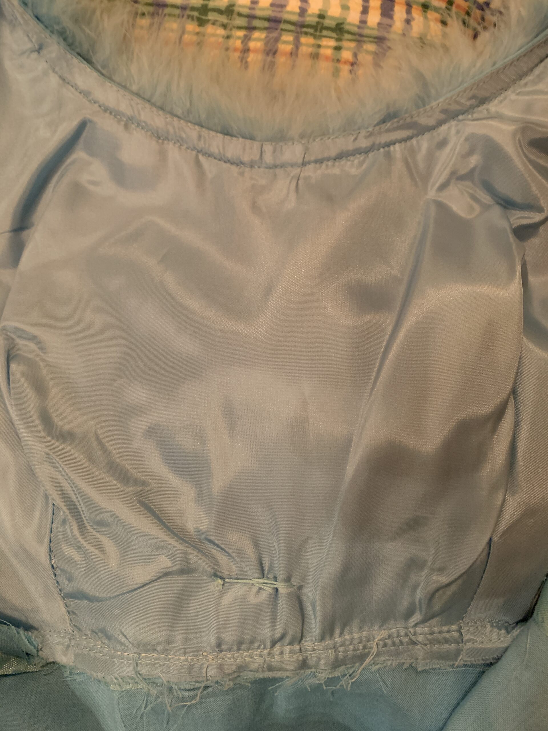 Interior view of the vintage 1960s cocktail dress showing the light blue satin lining and construction details.