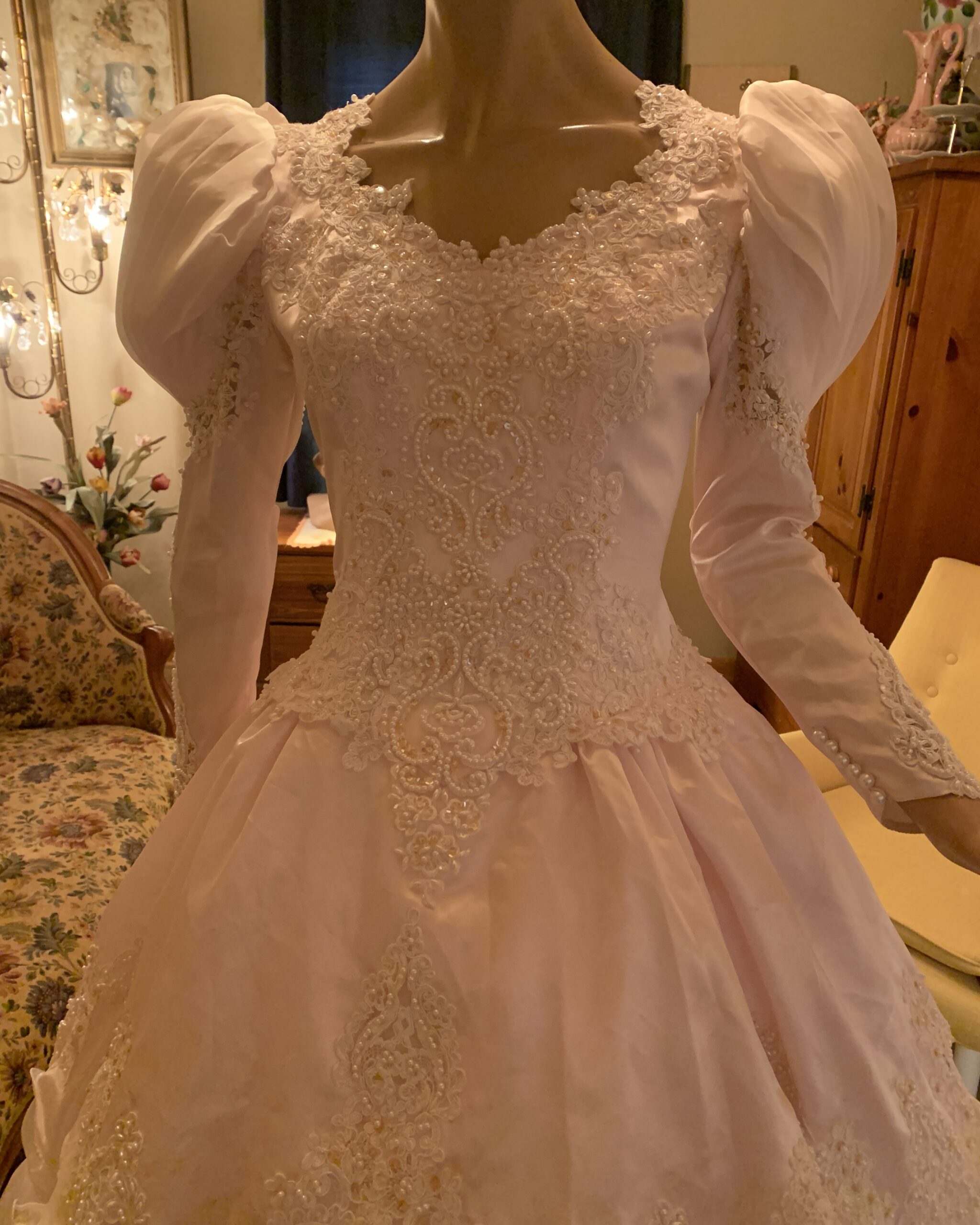 Close-up of beaded lace bodice on vintage blush pink wedding gown with pearl embellishment and romantic sweetheart neckline.