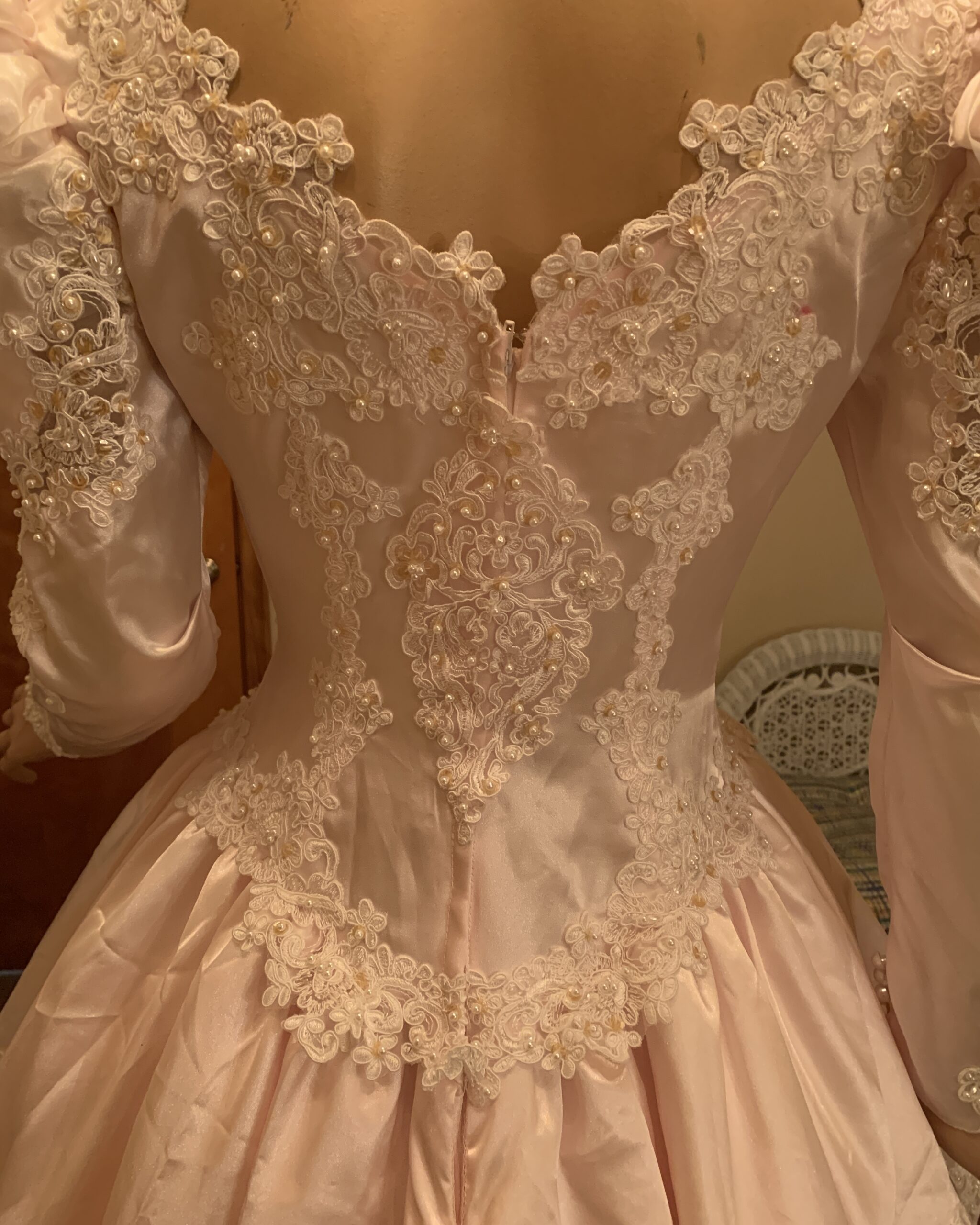 Close-up of illusion lace back on vintage blush pink bridal gown featuring intricate appliqué, pearls, and beadwork.