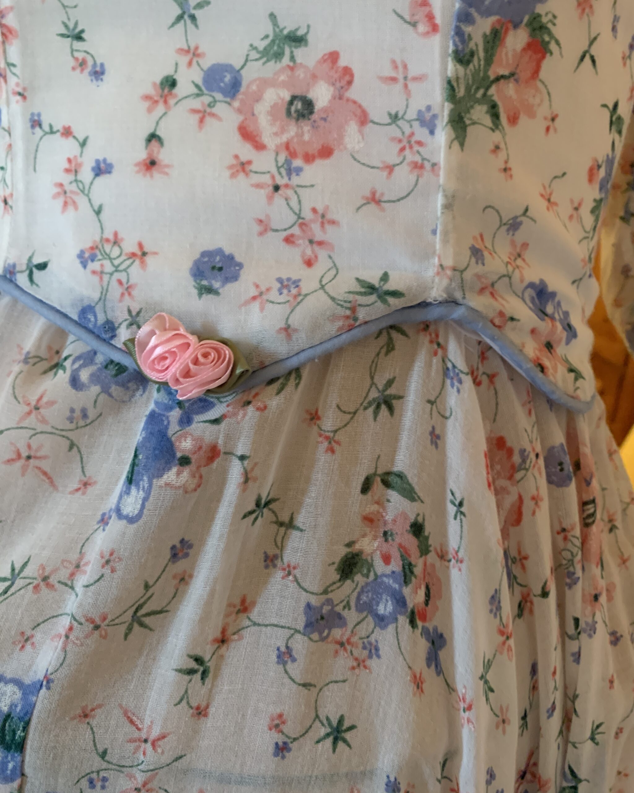 Close-up of peplum waistline with blue piping and pink ribbon rose accents on handmade western prairie dress.