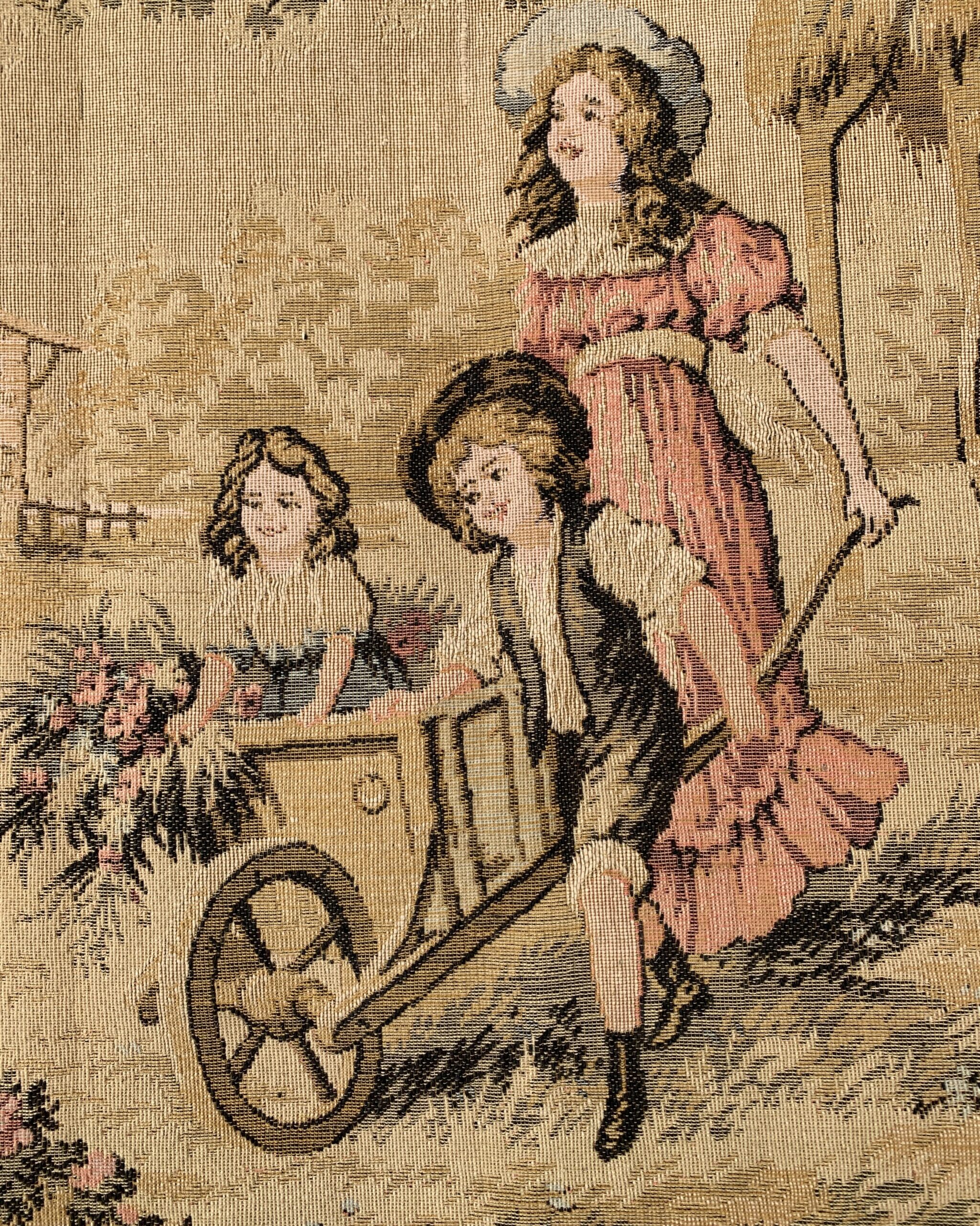 Detail of children with a flower-filled garden cart beside a woman in a pink dress on a vintage woven pastoral wall hanging.