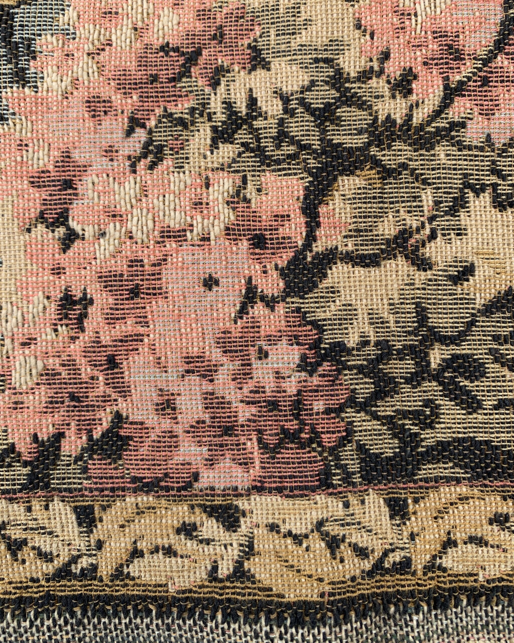 Close-up of pink flowering shrubs and the decorative woven border on an early European pastoral wall hanging.