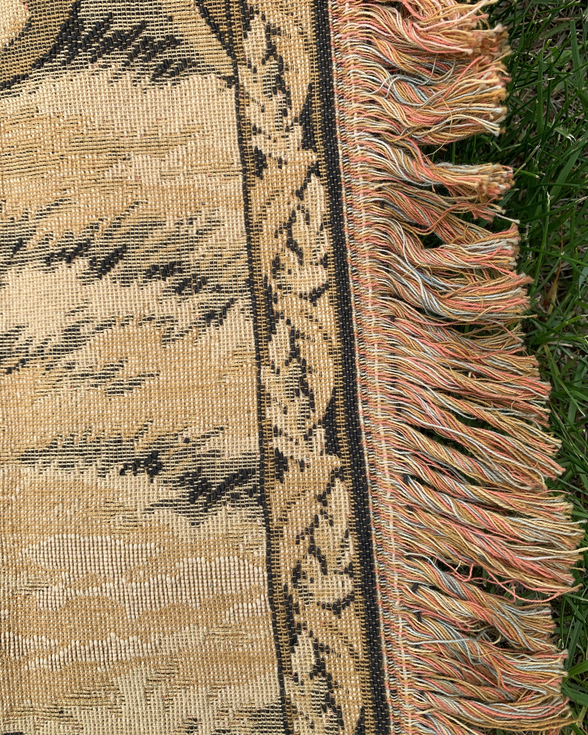 Detail of the original multicolored fringe and woven floral border on a vintage European wall hanging.