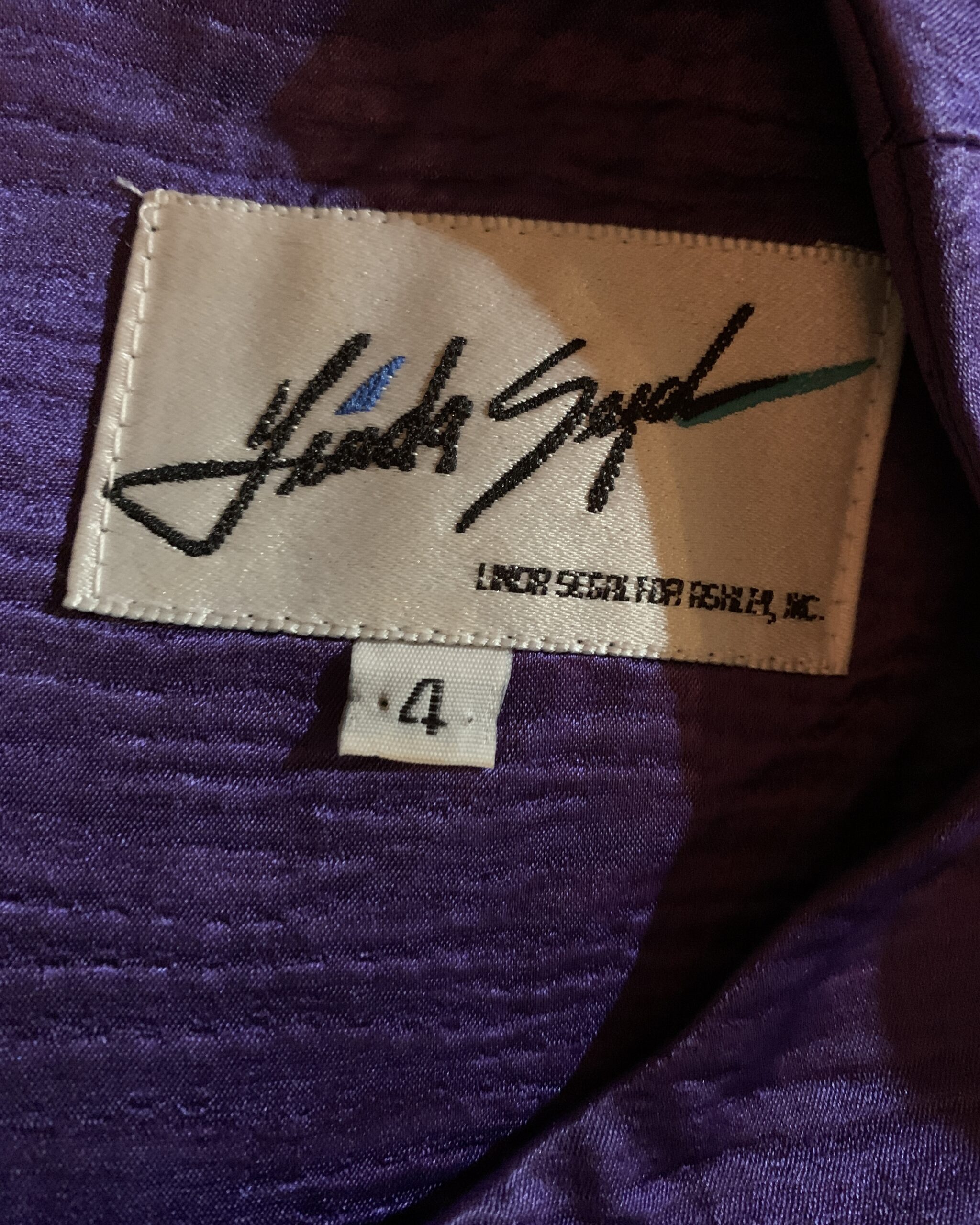 Close-up of the Linda Segal designer label sewn into the purple satin lining of a vintage evening gown.