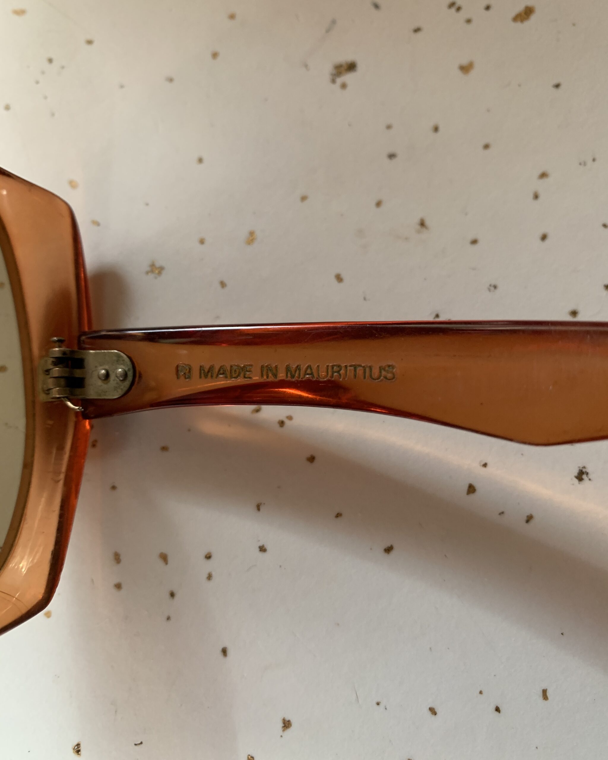 Close-up of the temple arm stamped “Made in Mauritius” on vintage oversized amber ombré sunglasses.