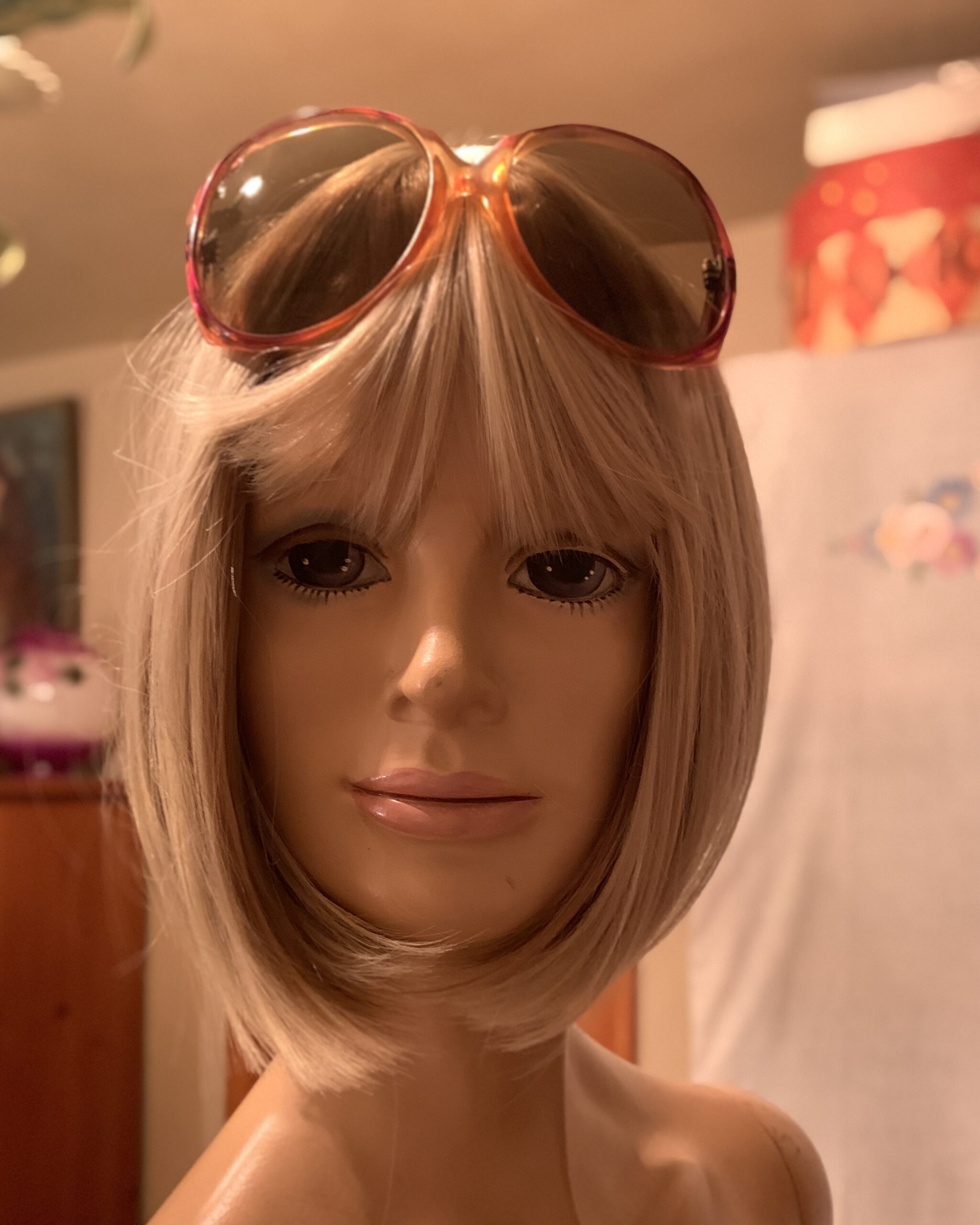 Vintage 1970s oversized amber ombré sunglasses resting on a mannequin’s head showing the frame shape and tinted lenses.