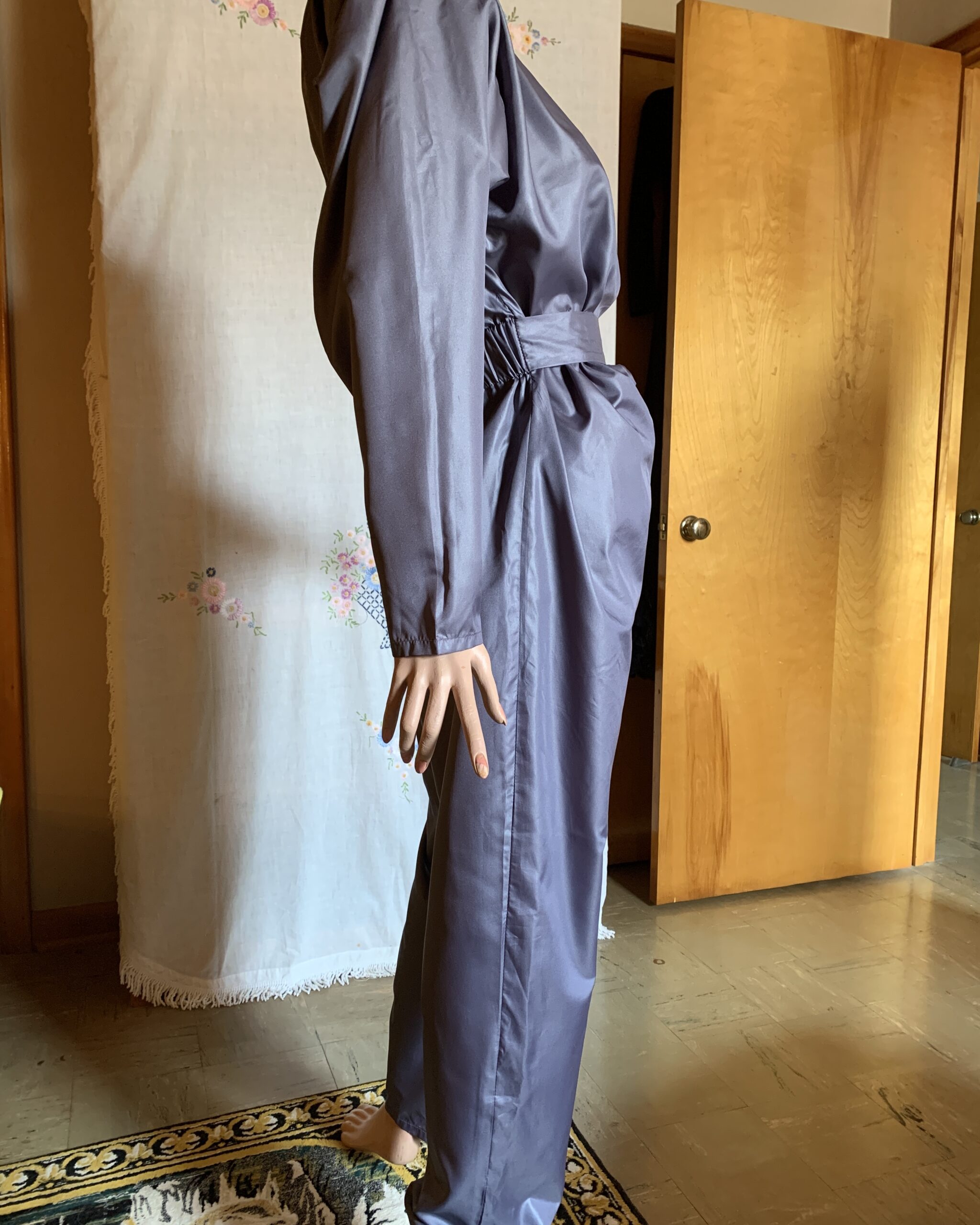 Side profile of vintage Antonio Ruspoli belted jumpsuit with front draping, long sleeves, and tapered leg design.