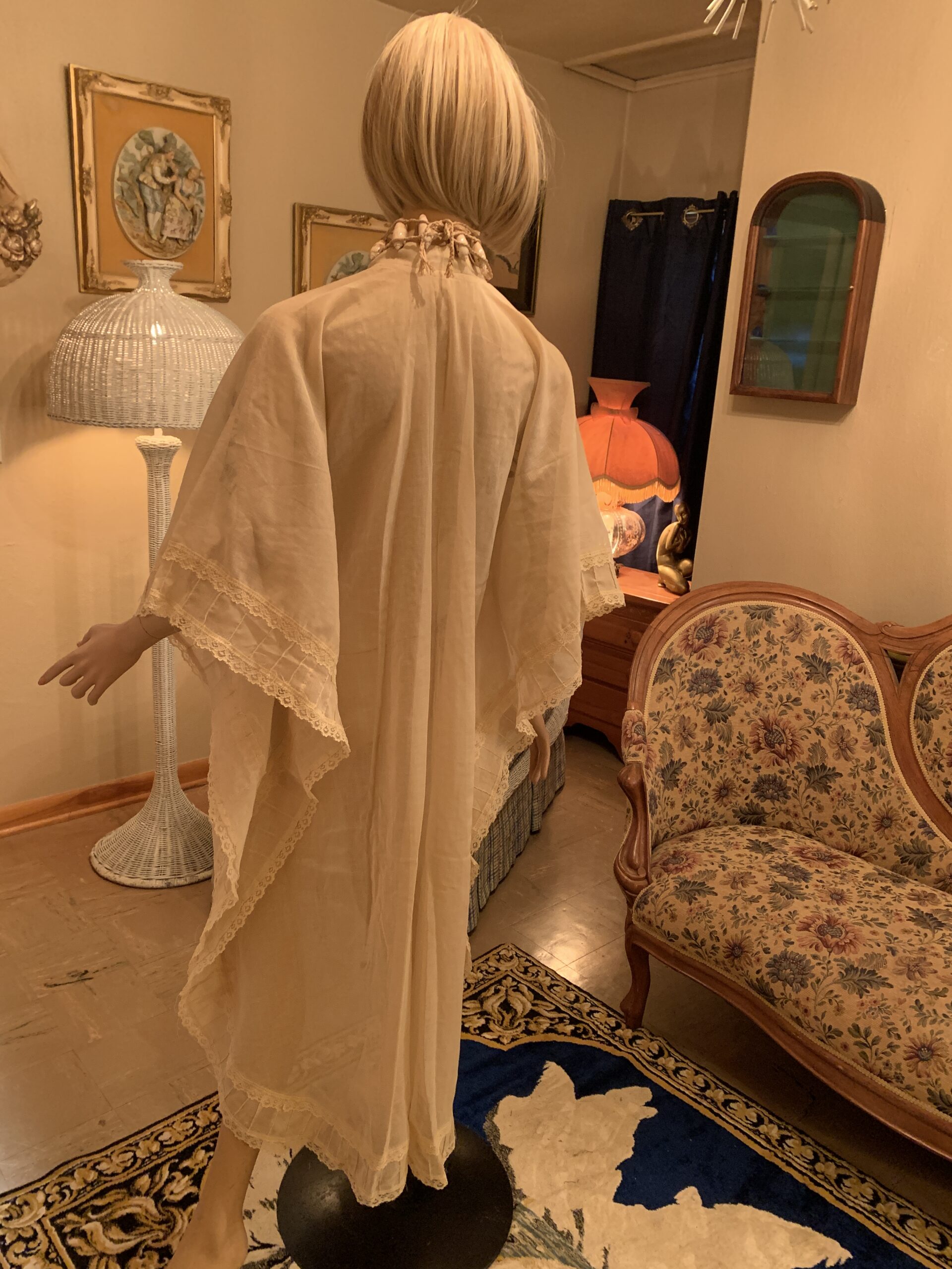 Back view of a vintage ivory cotton caftan showing the dramatic cape-style drape, flowing silhouette, and lace-trimmed sleeves.