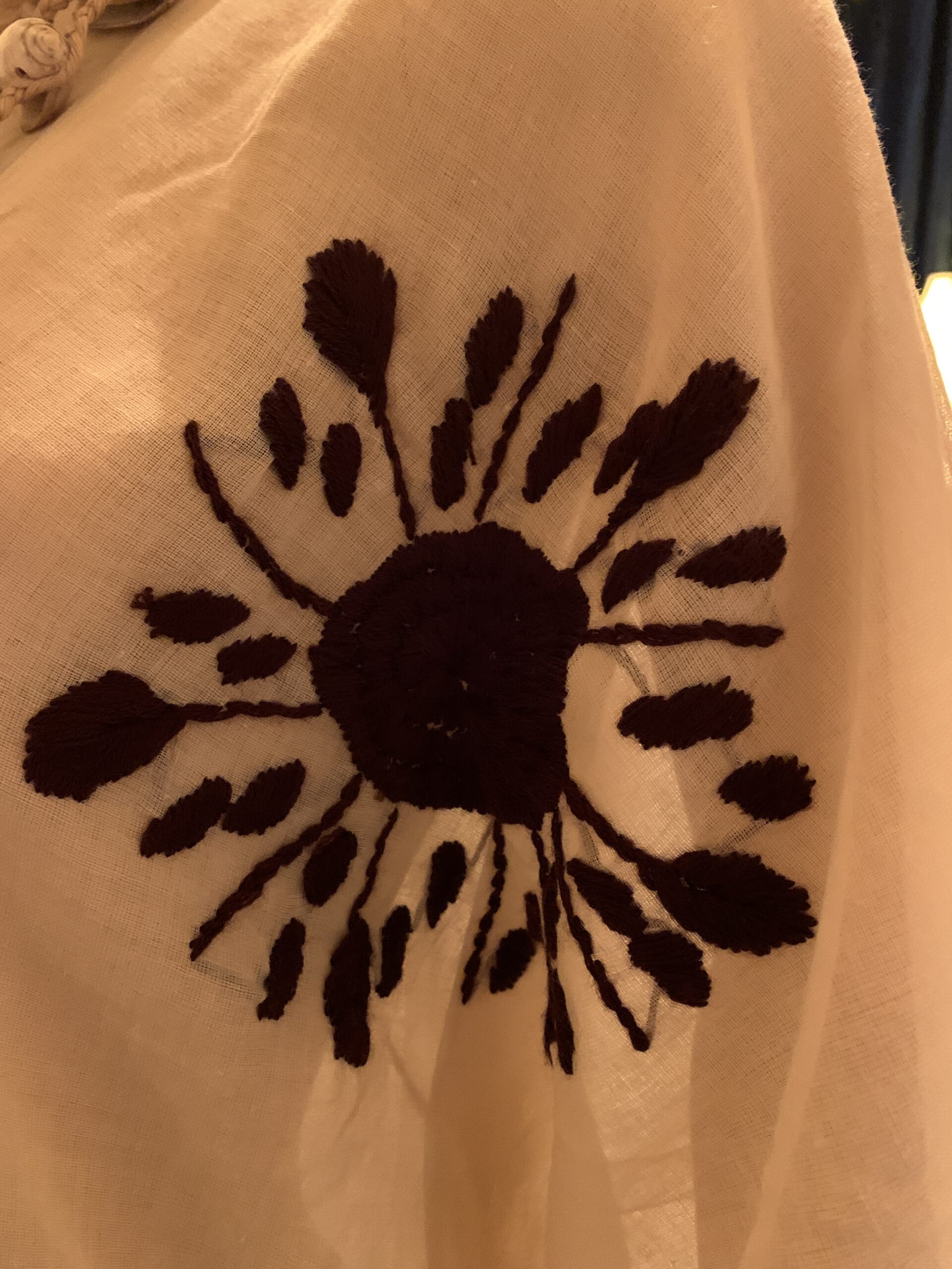 Close-up of the bold black floral embroidery on the vintage ivory cotton caftan, highlighting the raised handcrafted stitching.