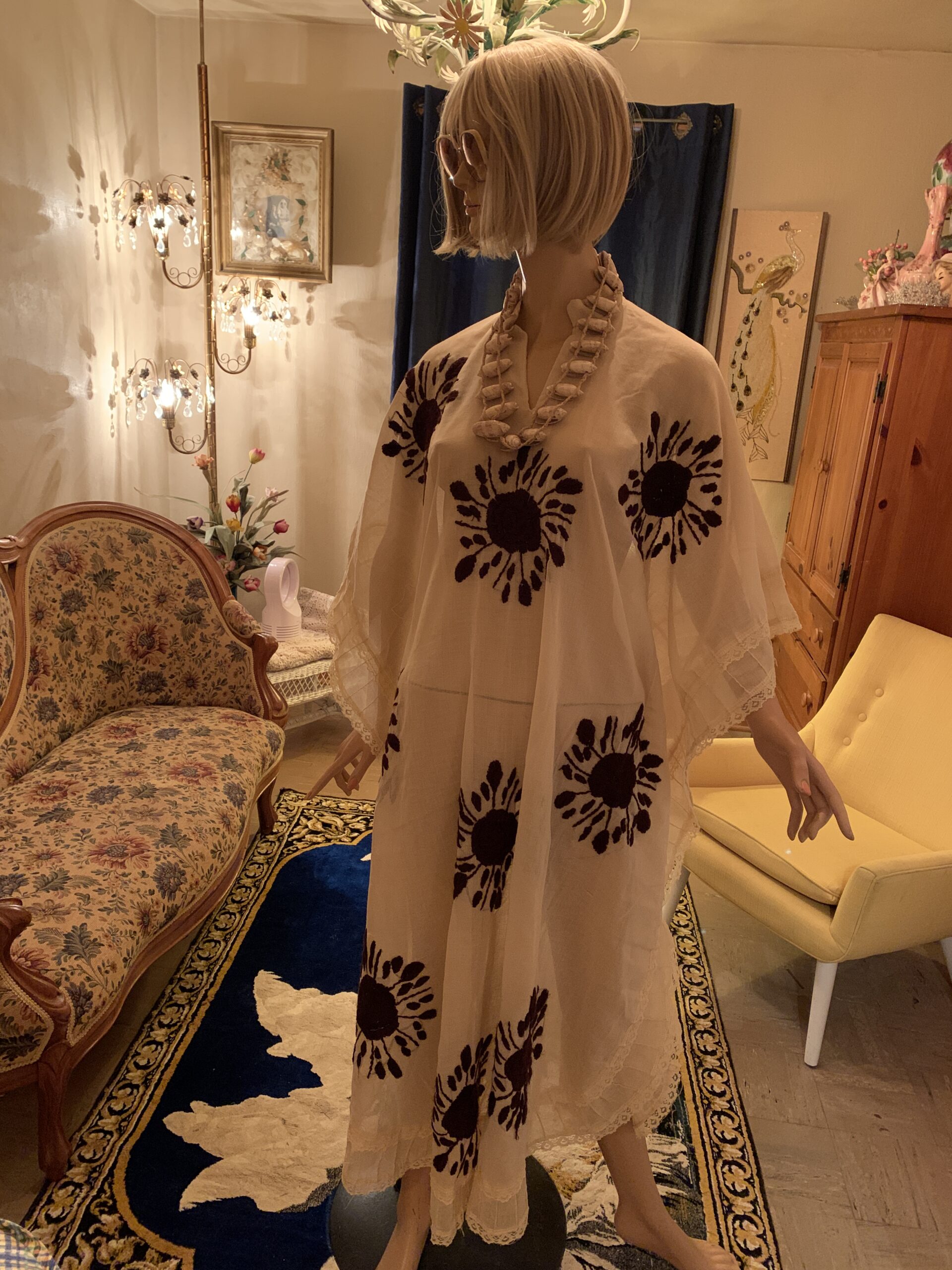 Three-quarter view of a vintage ivory embroidered cotton caftan featuring bold black floral motifs, wide sleeves, and a flowing silhouette.