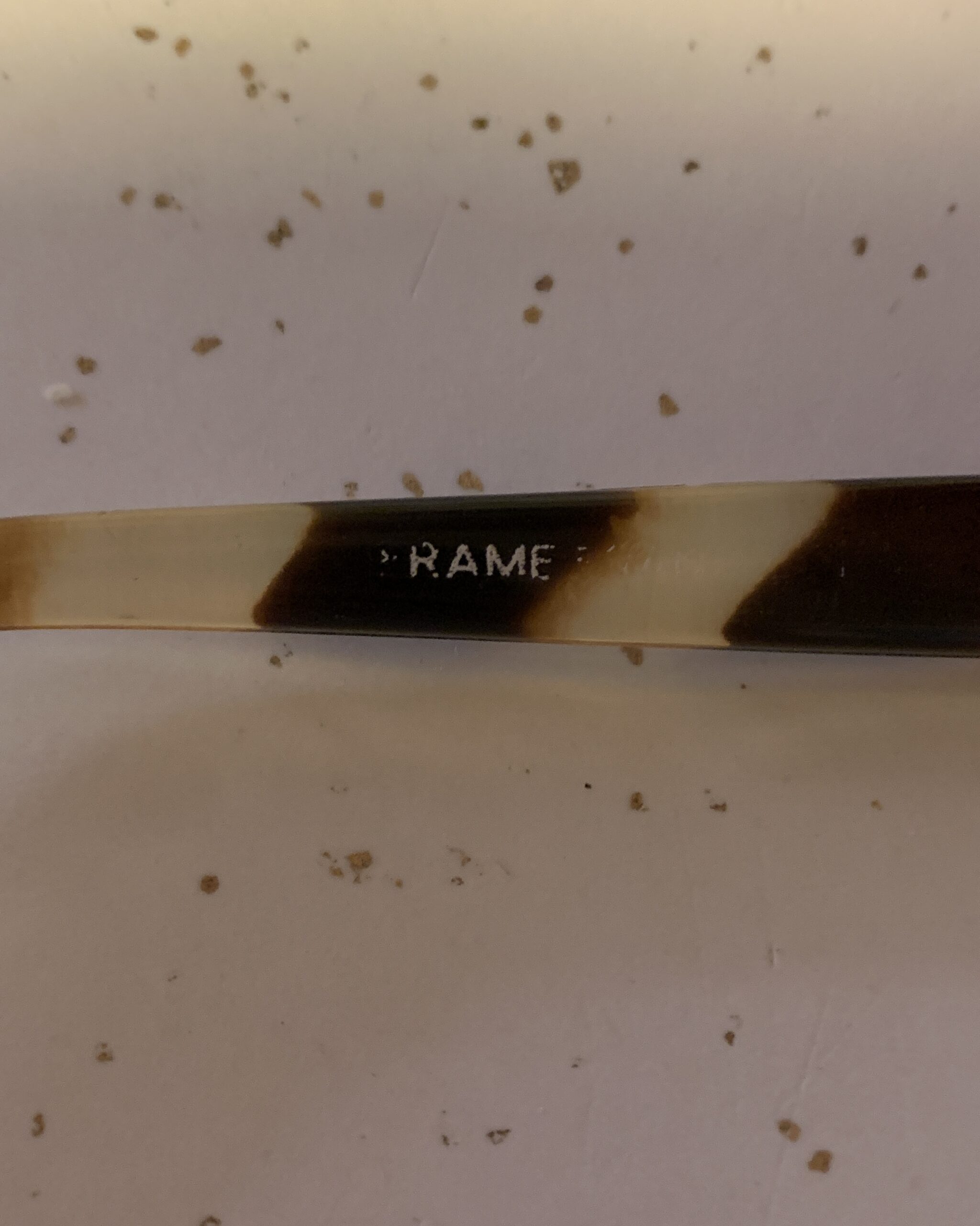 Close-up of the maker’s mark stamped inside the temple of vintage tortoiseshell sunglasses.