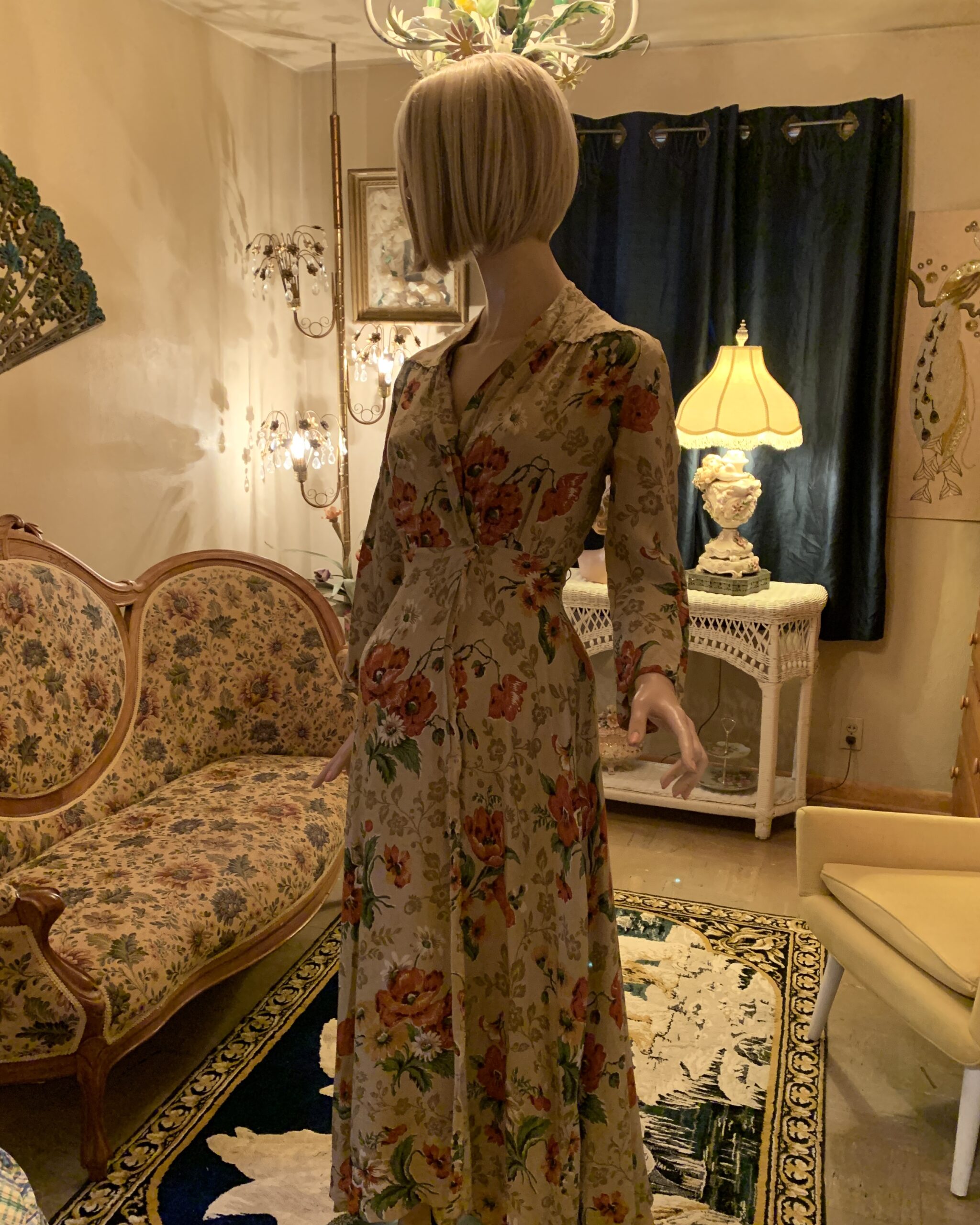 Vintage 1940s floral wrap dress featuring an allover poppy print, notched collar, fitted waist, and graceful drape photographed in a warmly lit vintage interior.