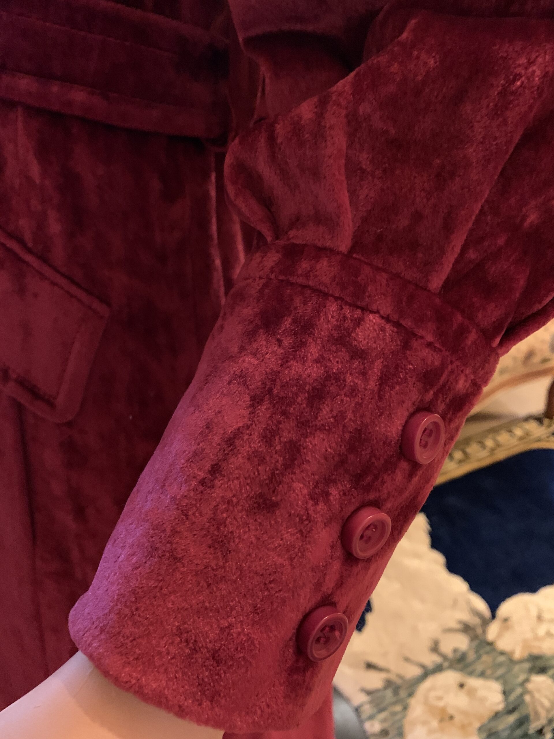 Close-up of the button cuff detail on a 1970s burgundy crushed velvet coat, highlighting the plush crushed velvet texture and tailored finish.