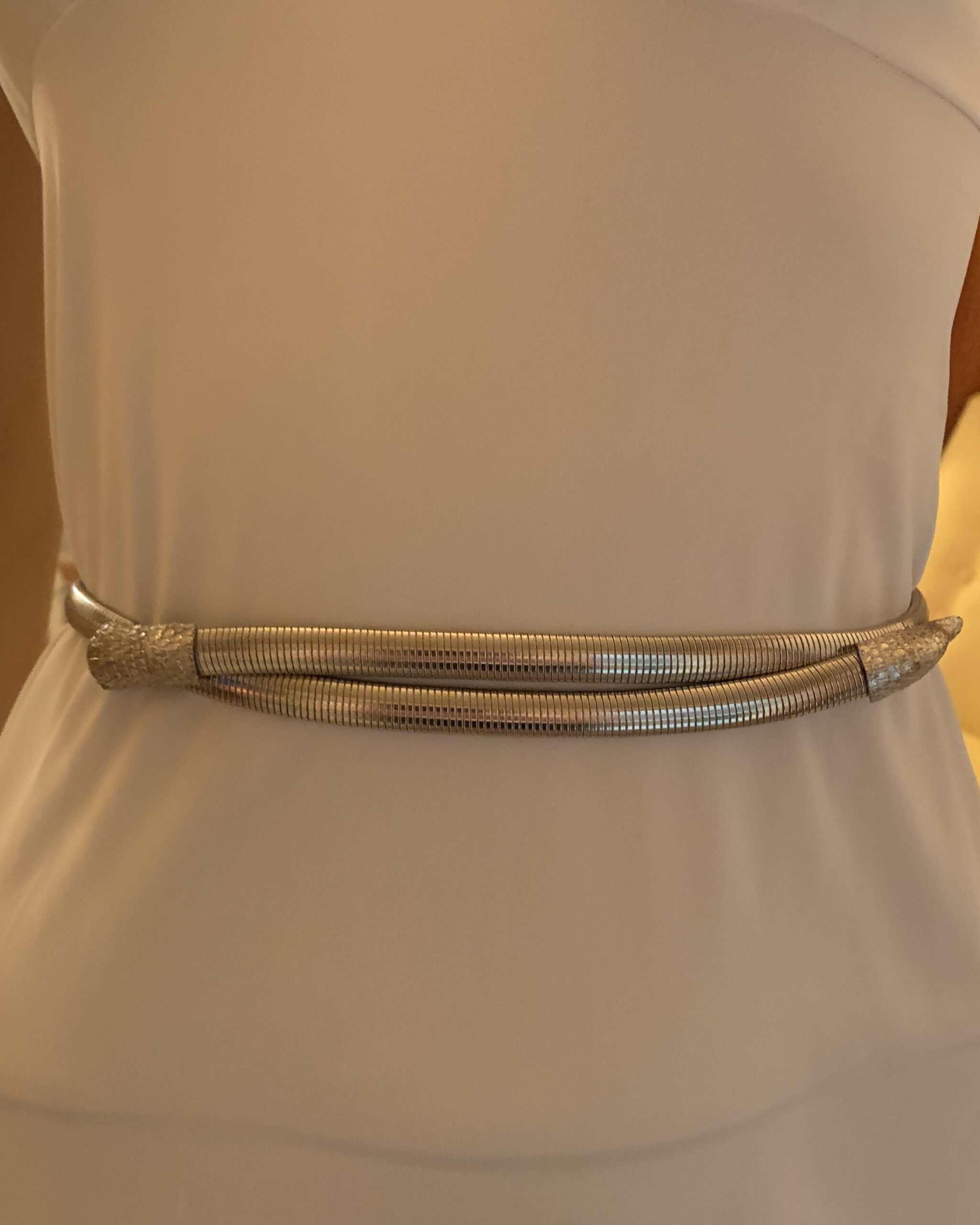Front view of Accessocraft silver-tone snake belt showing double-wrap coil design and sculptural snake-head ends.