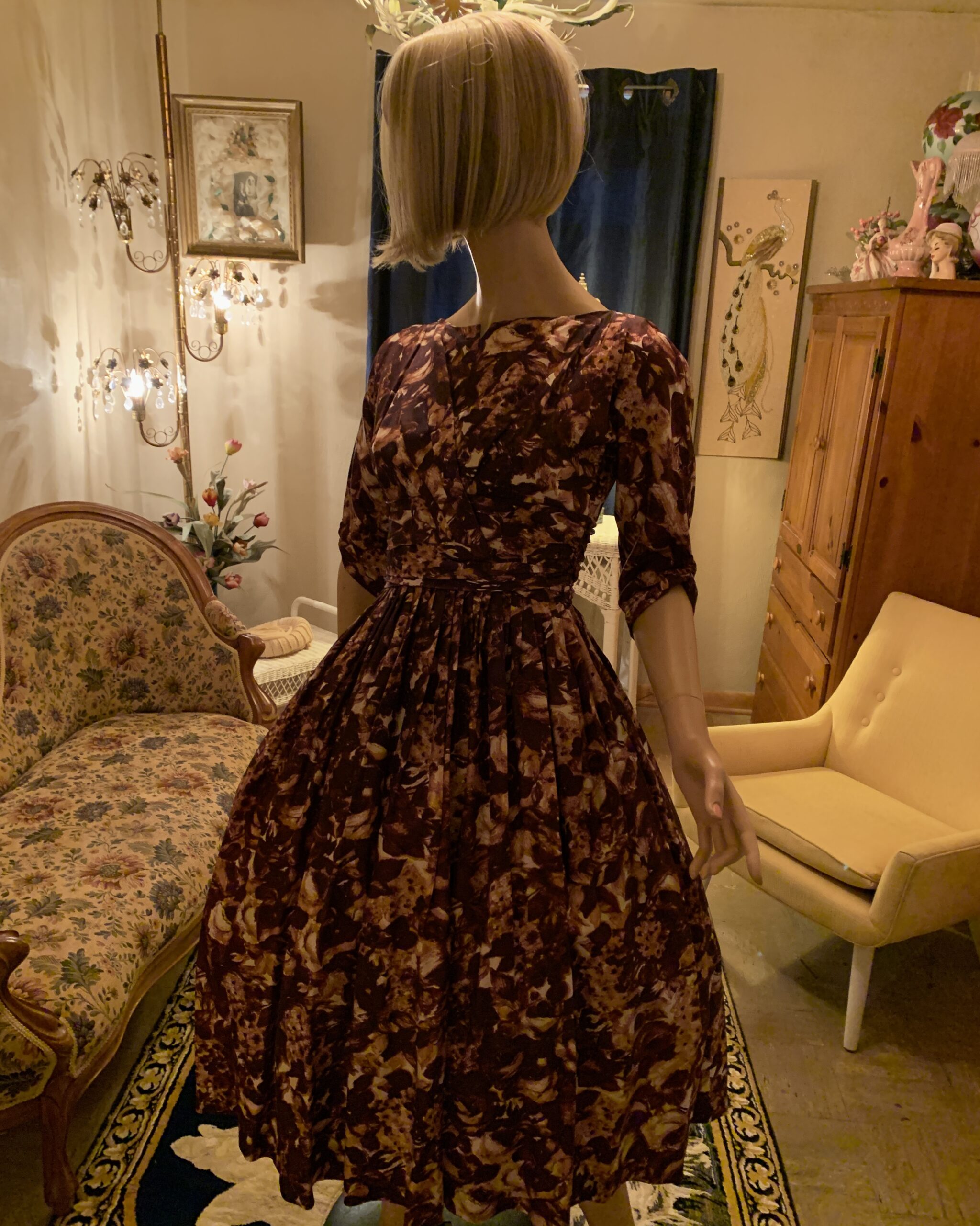 1950s Carol Craig New York chocolate brown abstract floral dress with a fitted bodice, three-quarter sleeves, and full pleated skirt displayed on a mannequin.