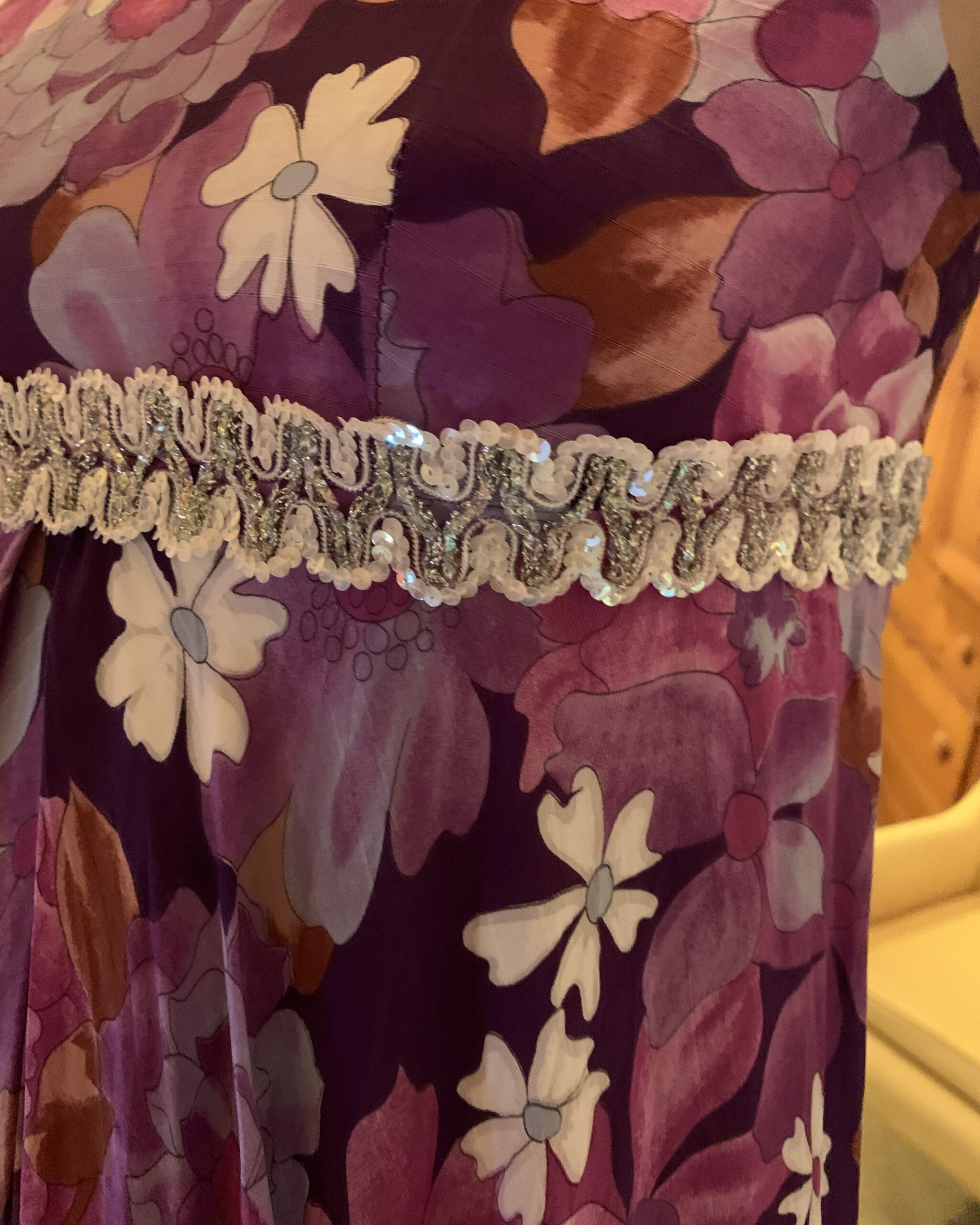 Close-up of the silver-and-white sequined braid trimming the empire waist of the floral jumpsuit.