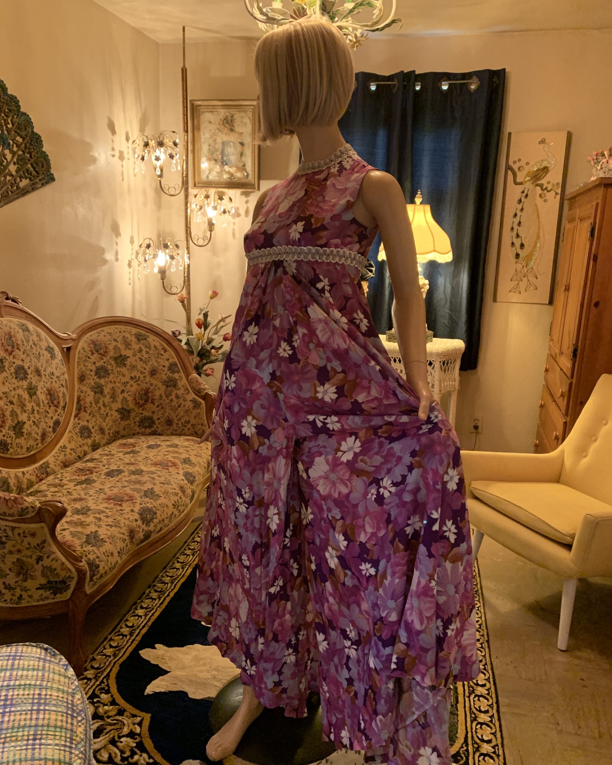 Vintage floral palazzo jumpsuit posed to reveal the dramatic width and flowing movement of the trouser legs.