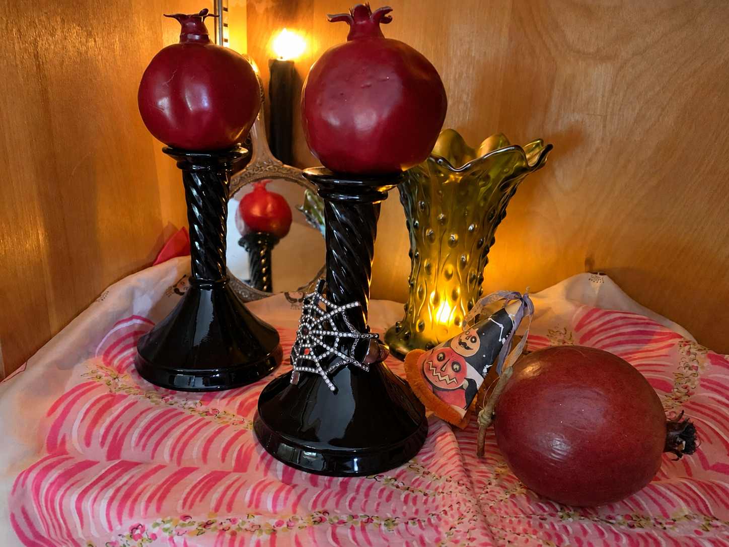 Vintage black amethyst glass taper candleholders styled in the Halloween Cabinet with red pomegranates and candlelight.