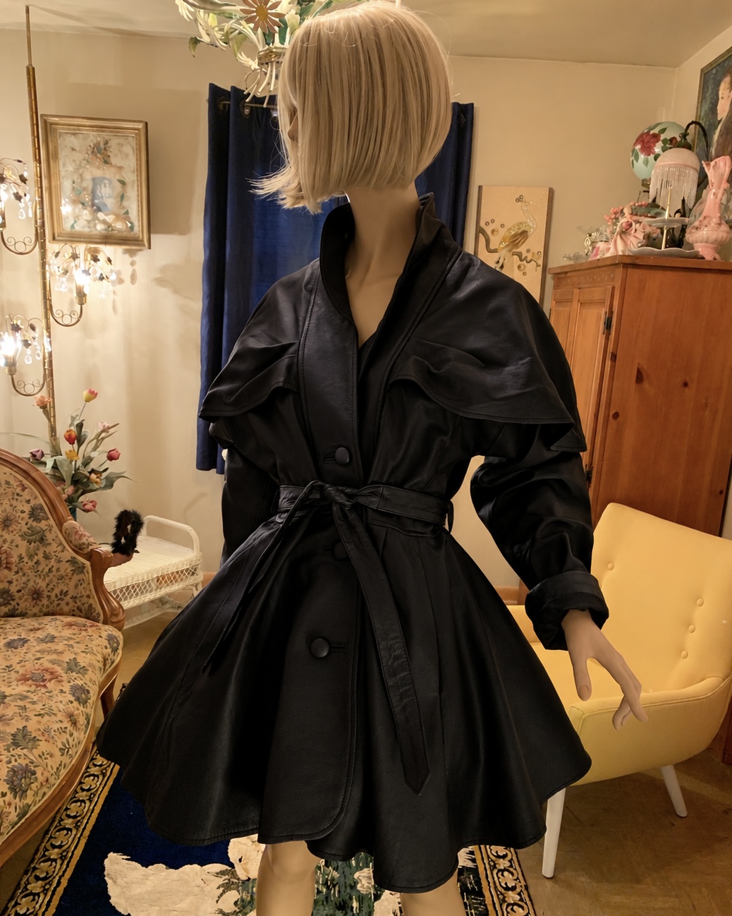 Deadstock vintage Sanzzini black leather coat featuring a cape-style shoulder overlay, leather-covered buttons, matching tie belt, and flared hem.