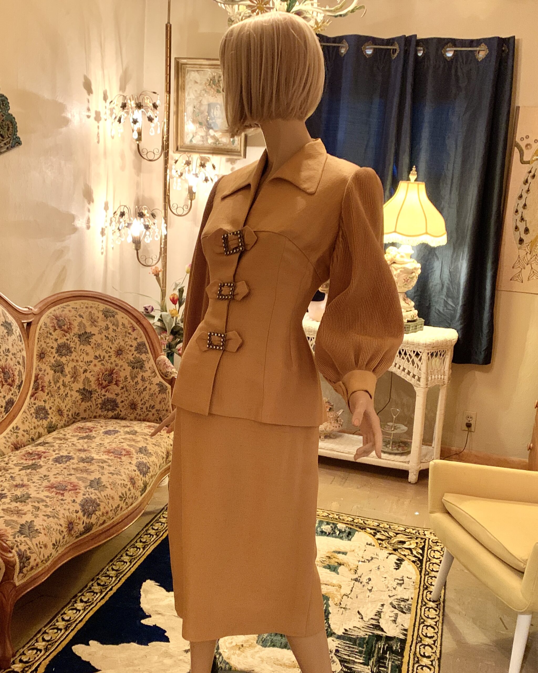 Angled front view of a camel Lilli Ann two-piece suit showing the pointed collar, shaped waist, and matching slim skirt.