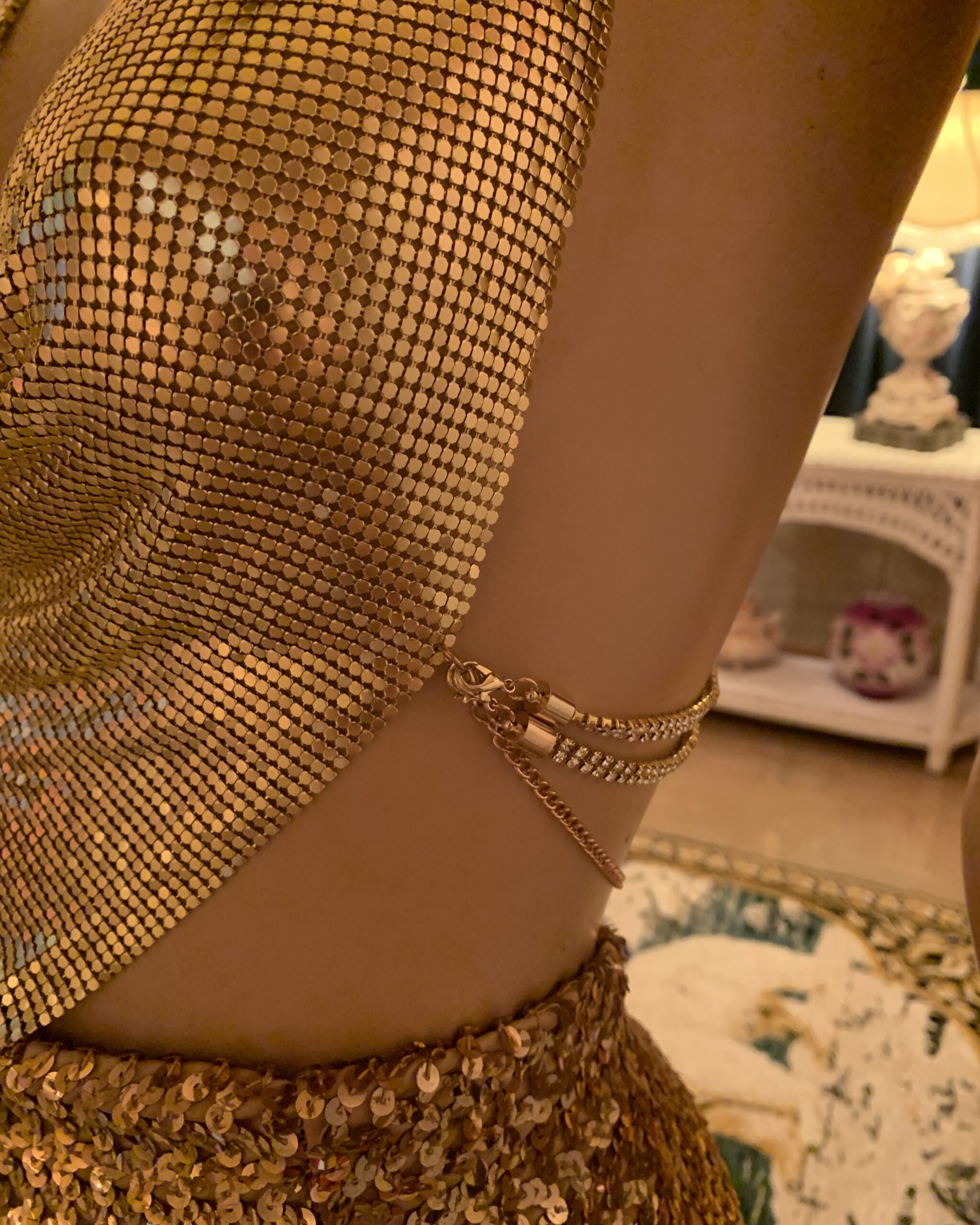 Close-up of the top’s side fastening, showing barrel clasps, rhinestone straps, and gold-tone chain.