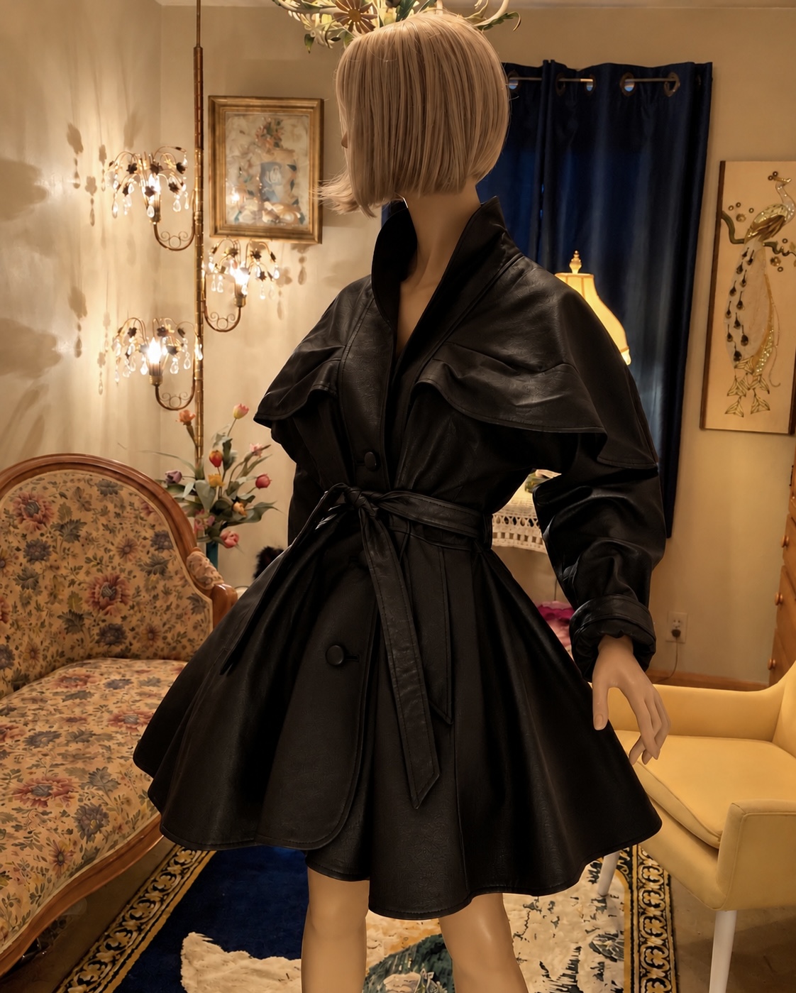 Vintage Sanzzini black leather coat with dramatic shoulder cape, standing collar, belted waist, and full flared skirt displayed on a mannequin.